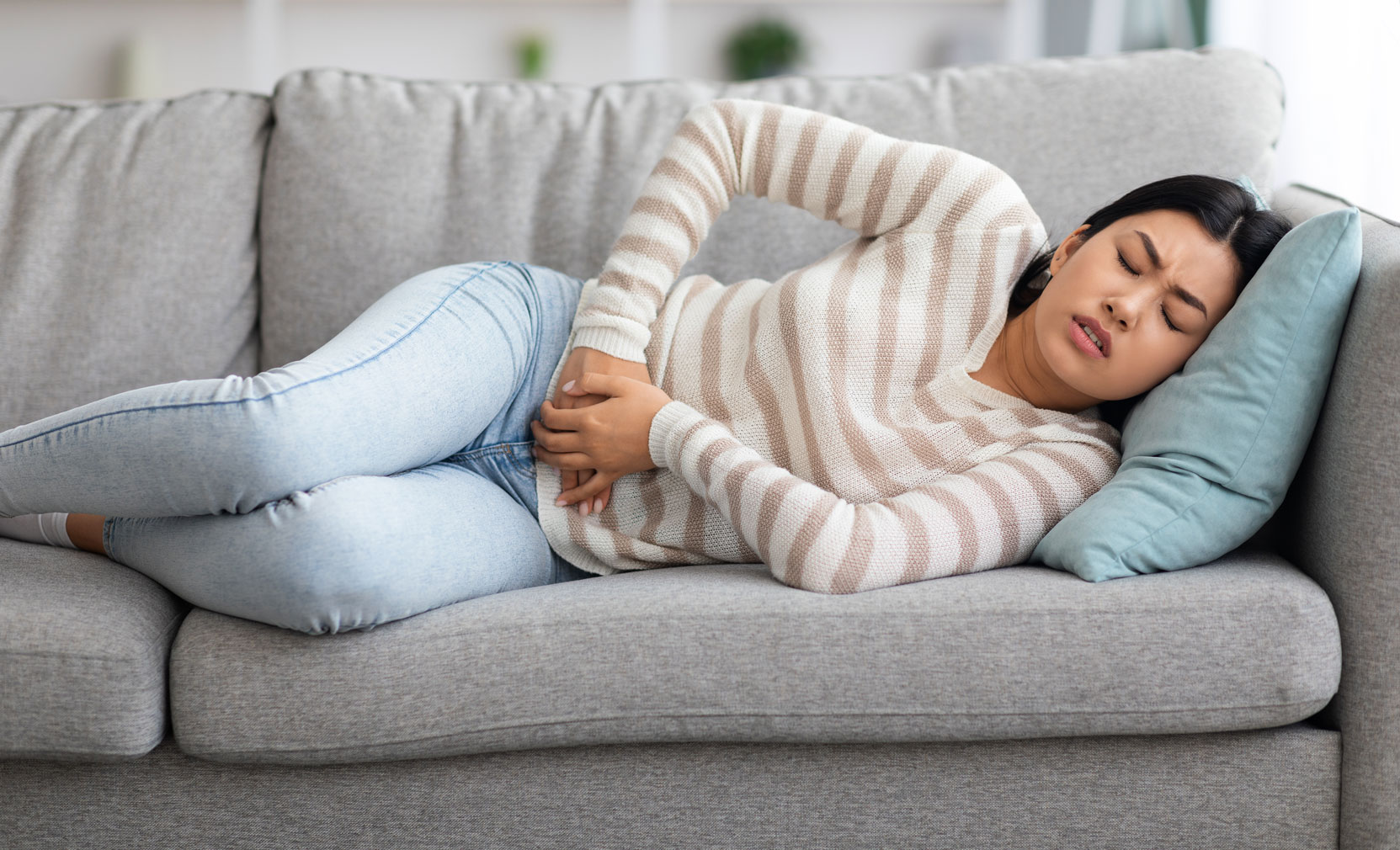 woman lying on her side in a couch with hands on her stomach