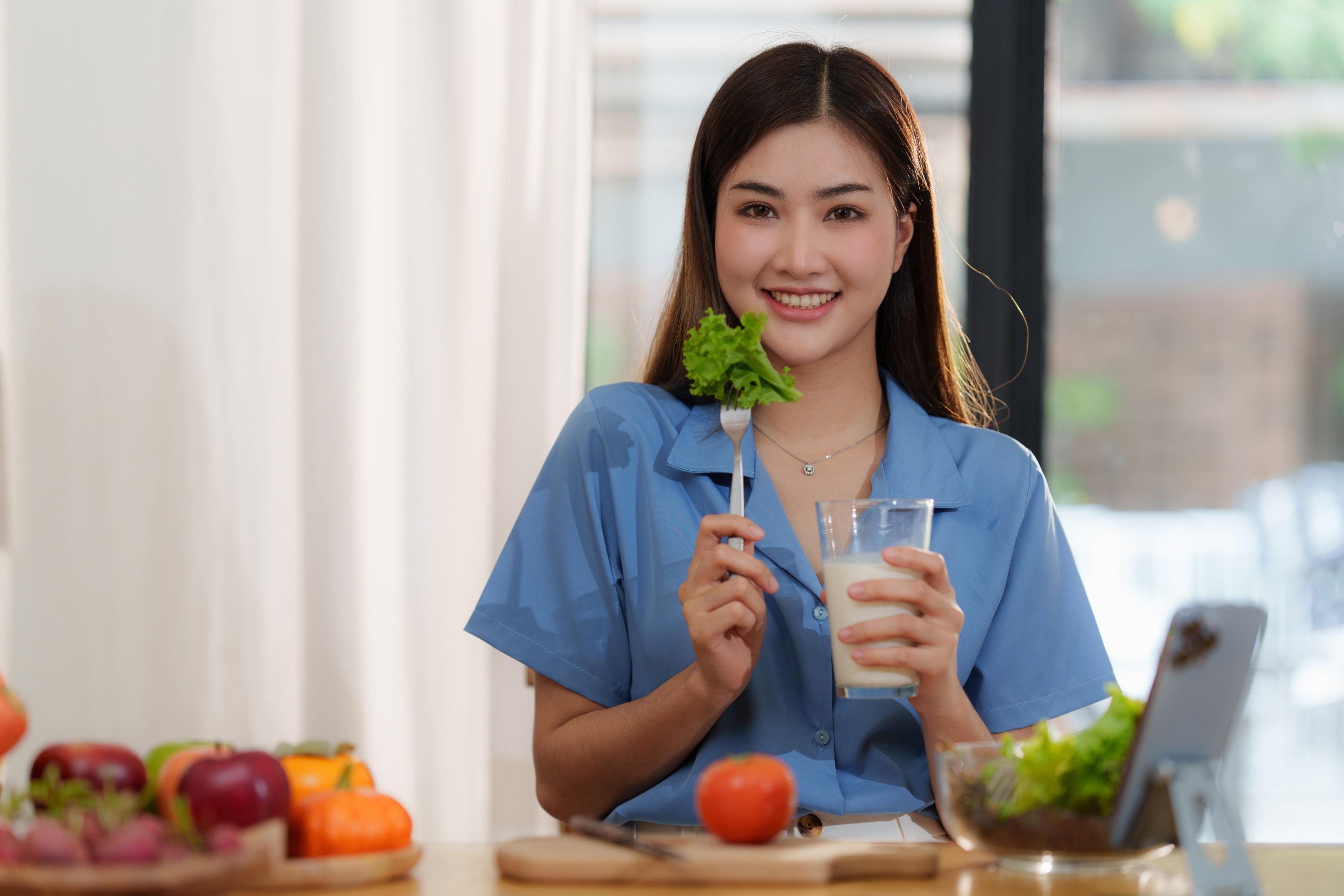 girl holding a glass of milk and brocolli