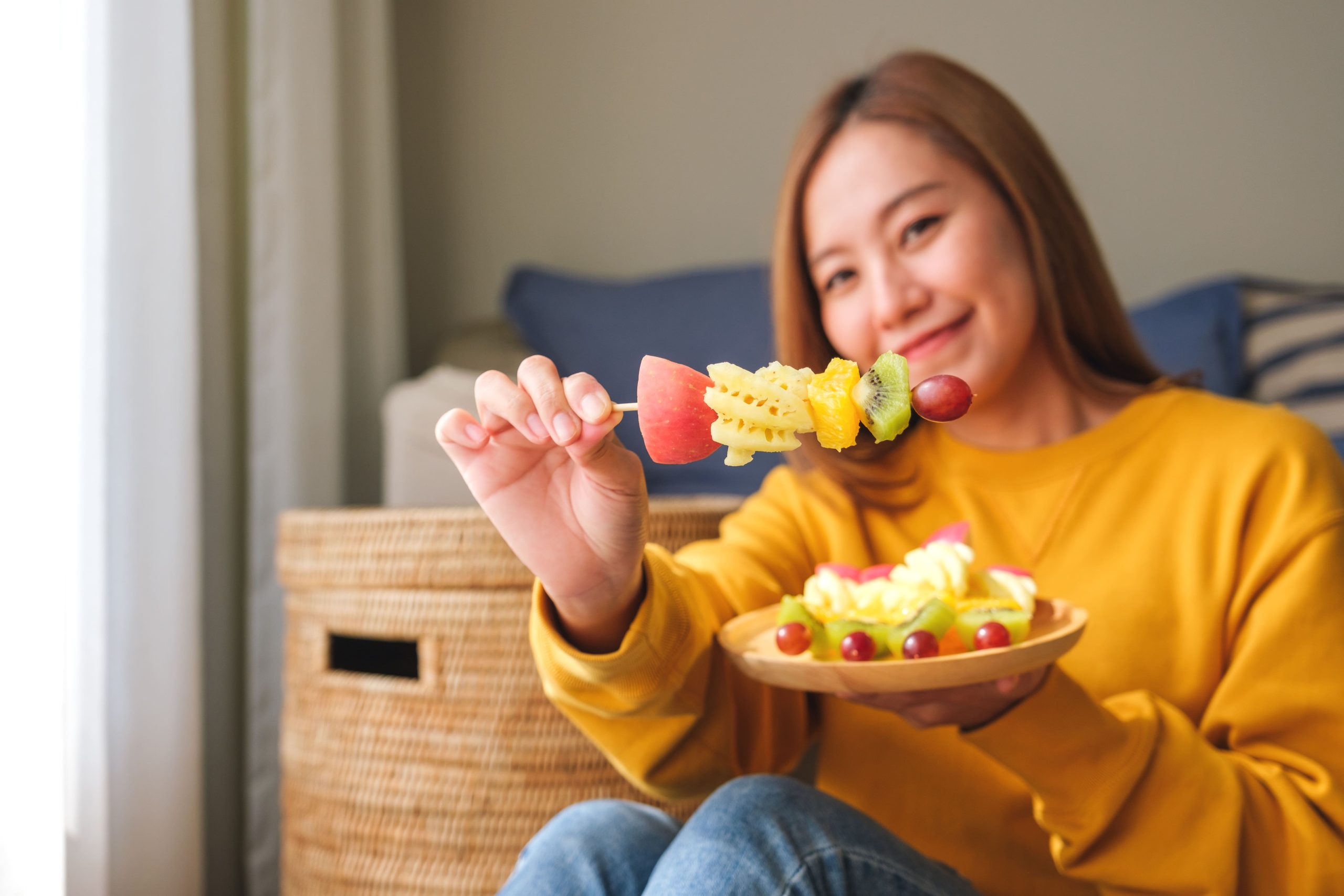 young woman eating fruits on skewers