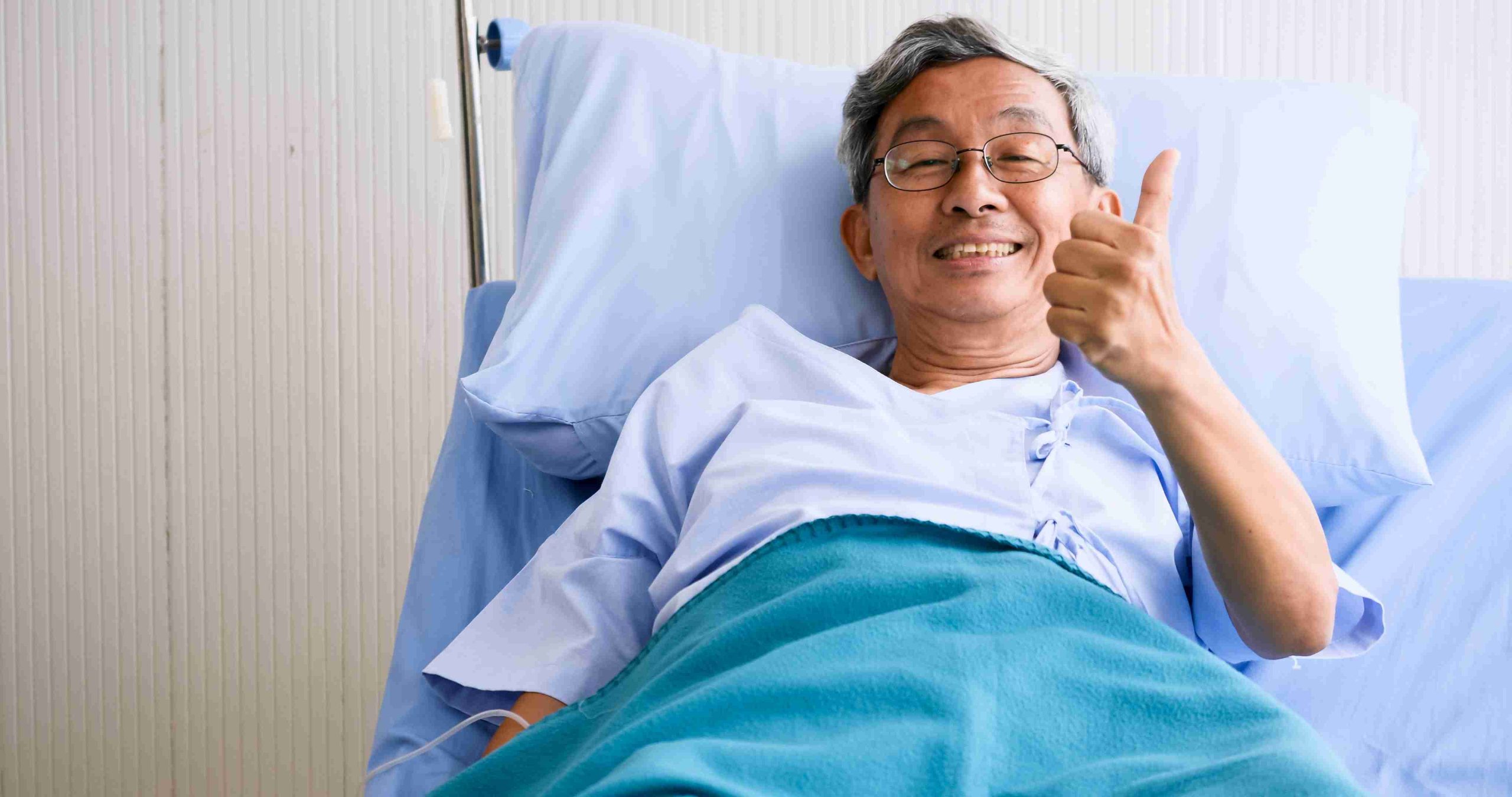 elderly male patient in the hospital bed giving a thumbs up