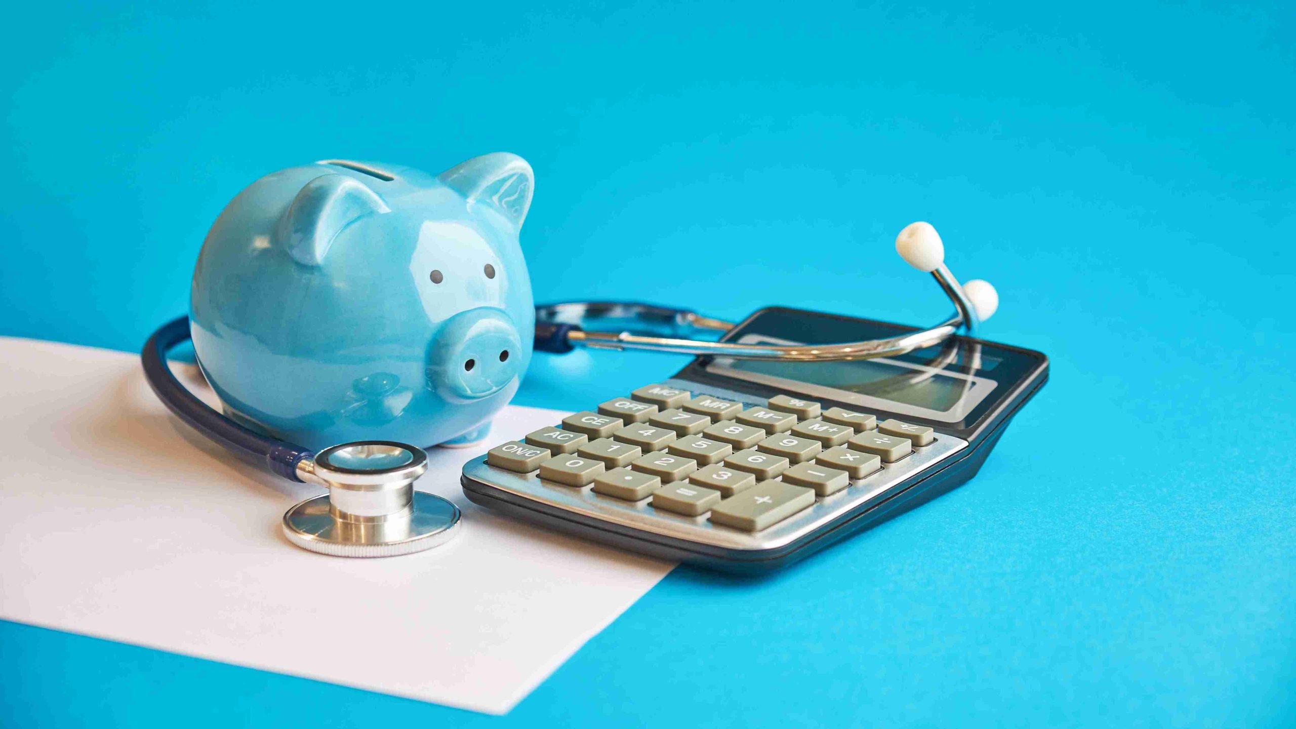 piggy bank, stethoscope, and calculator on the table