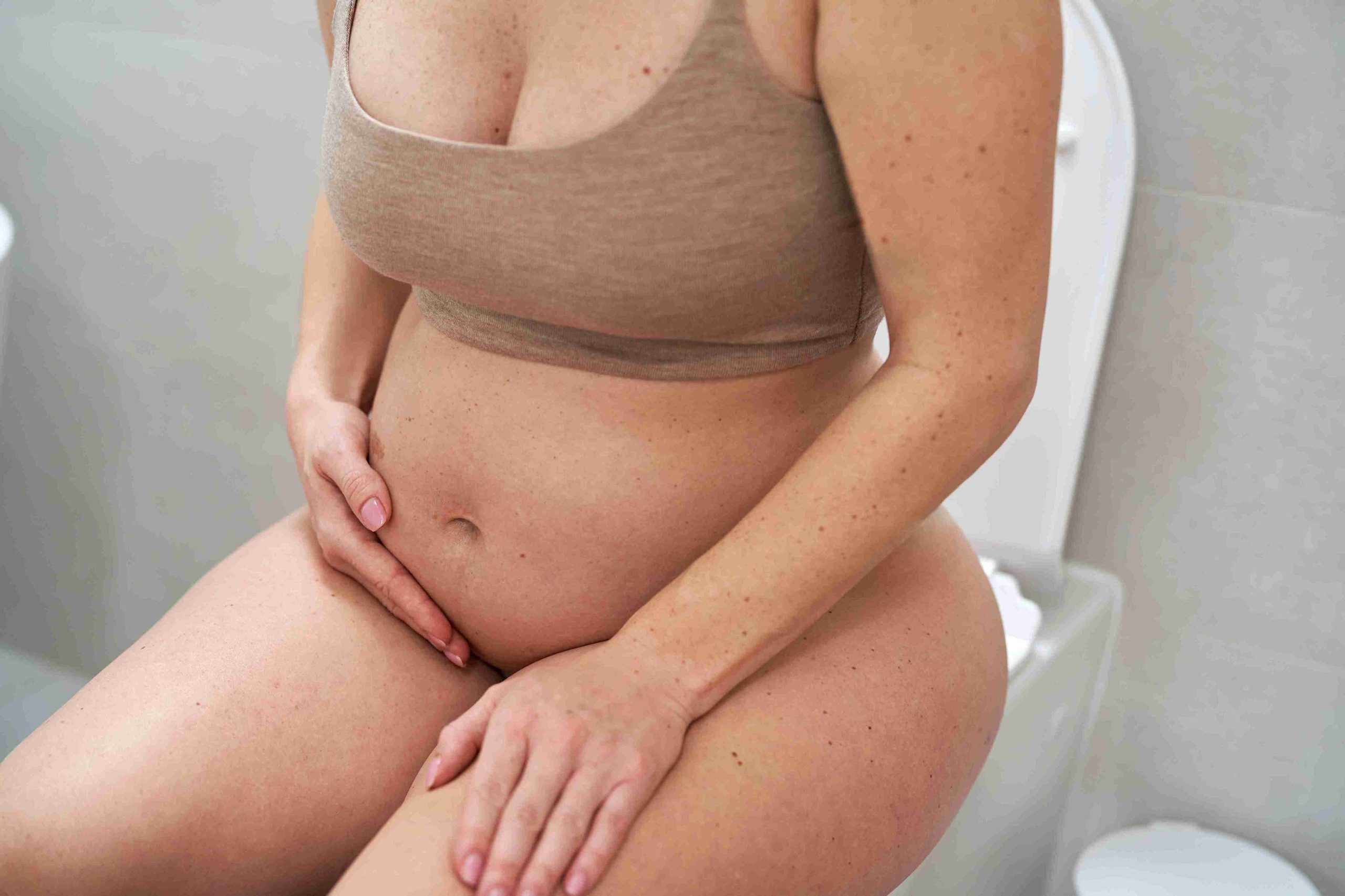 pregnant woman sitting on the toilet