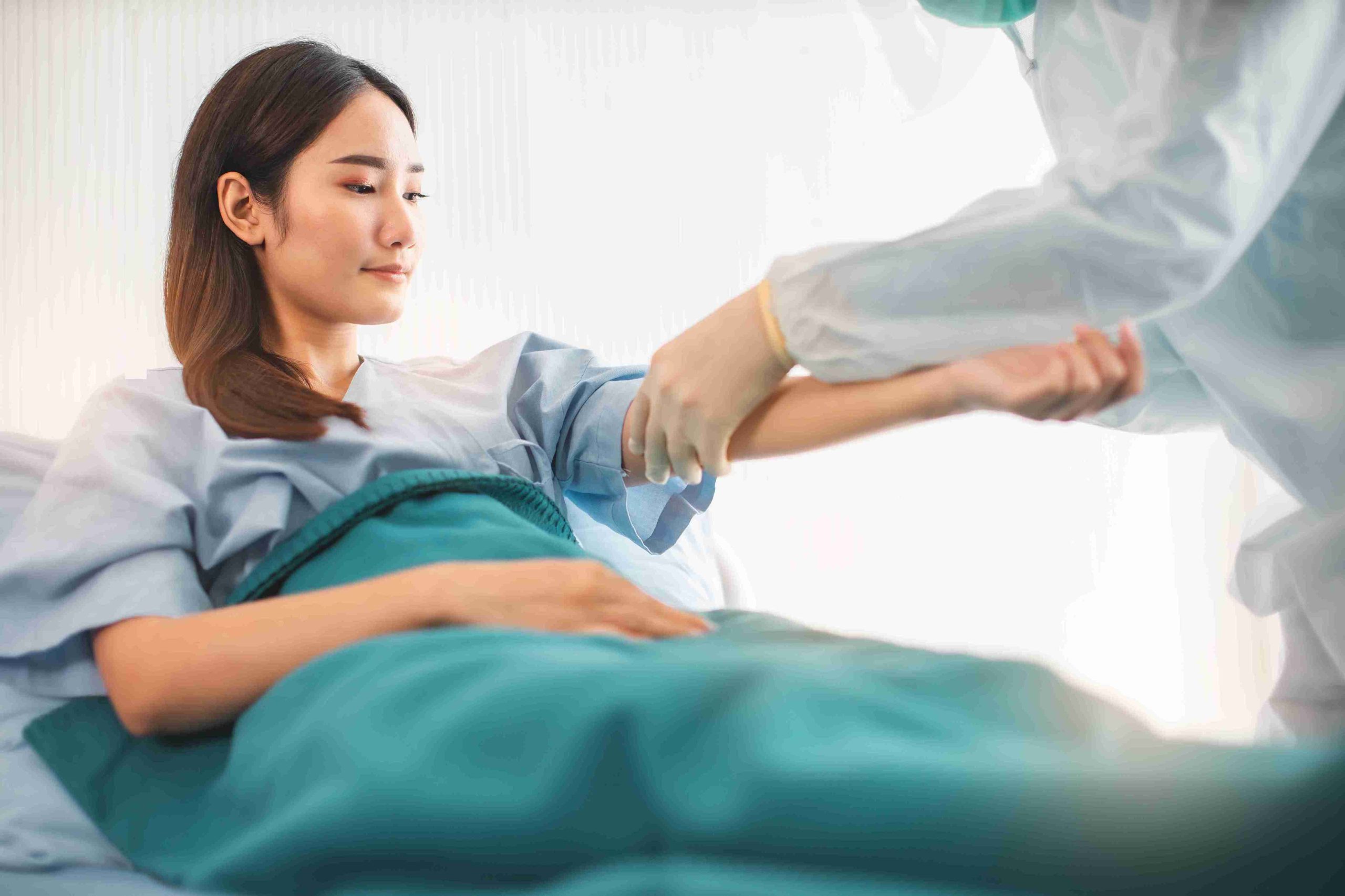 female patient in hospital bed being examined by a doctor
