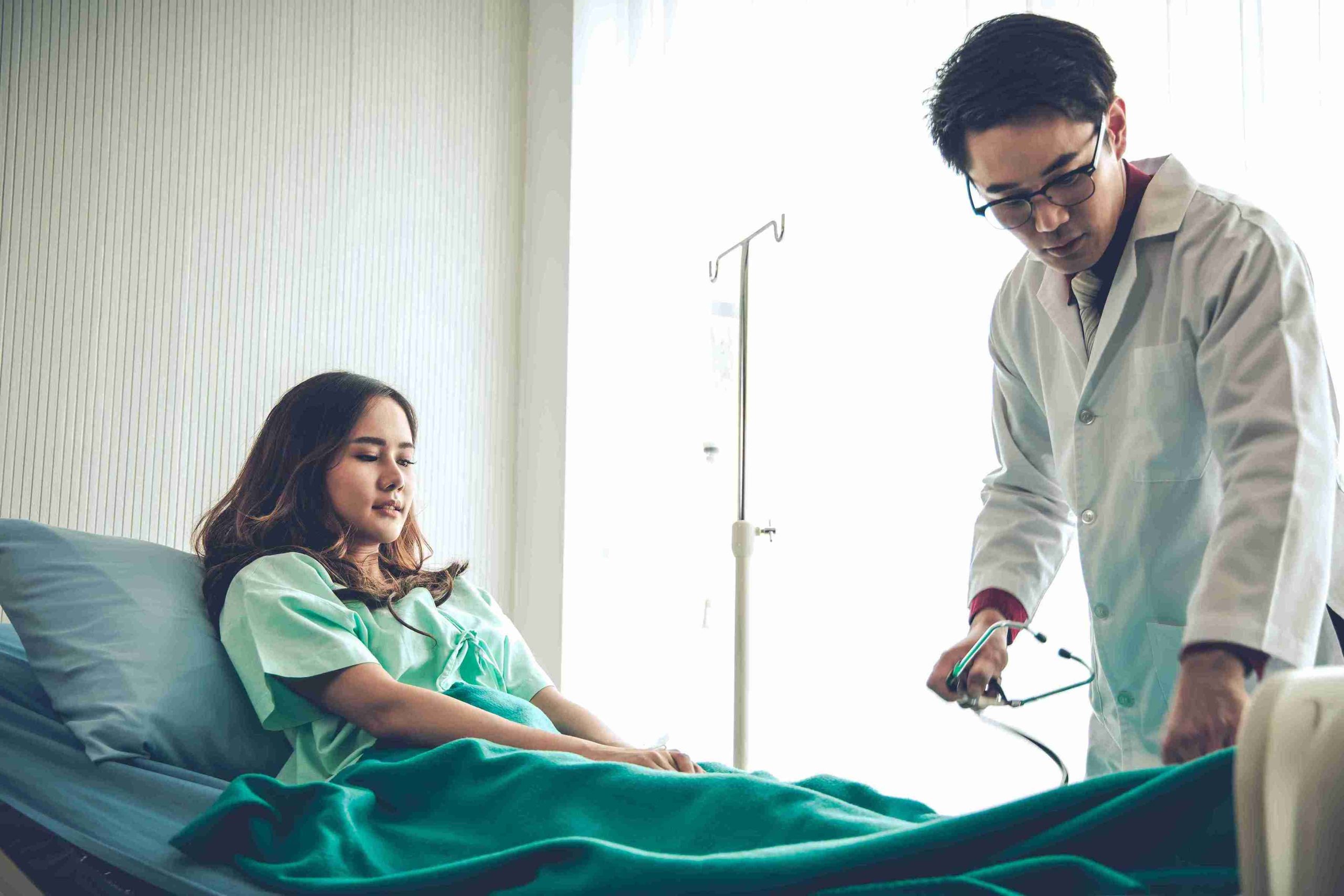 male doctor examining a female patient in hospital bed
