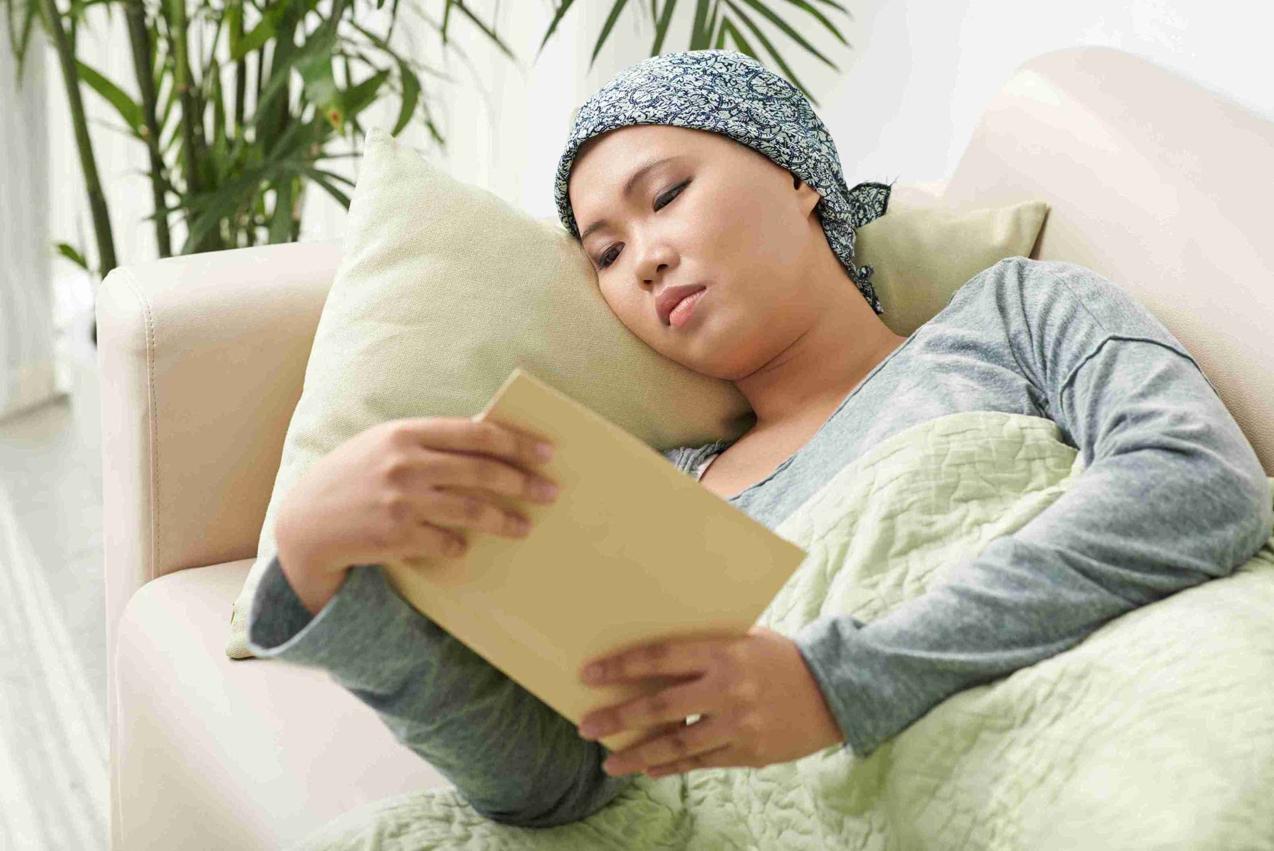 female cancer patient lying in bed reading