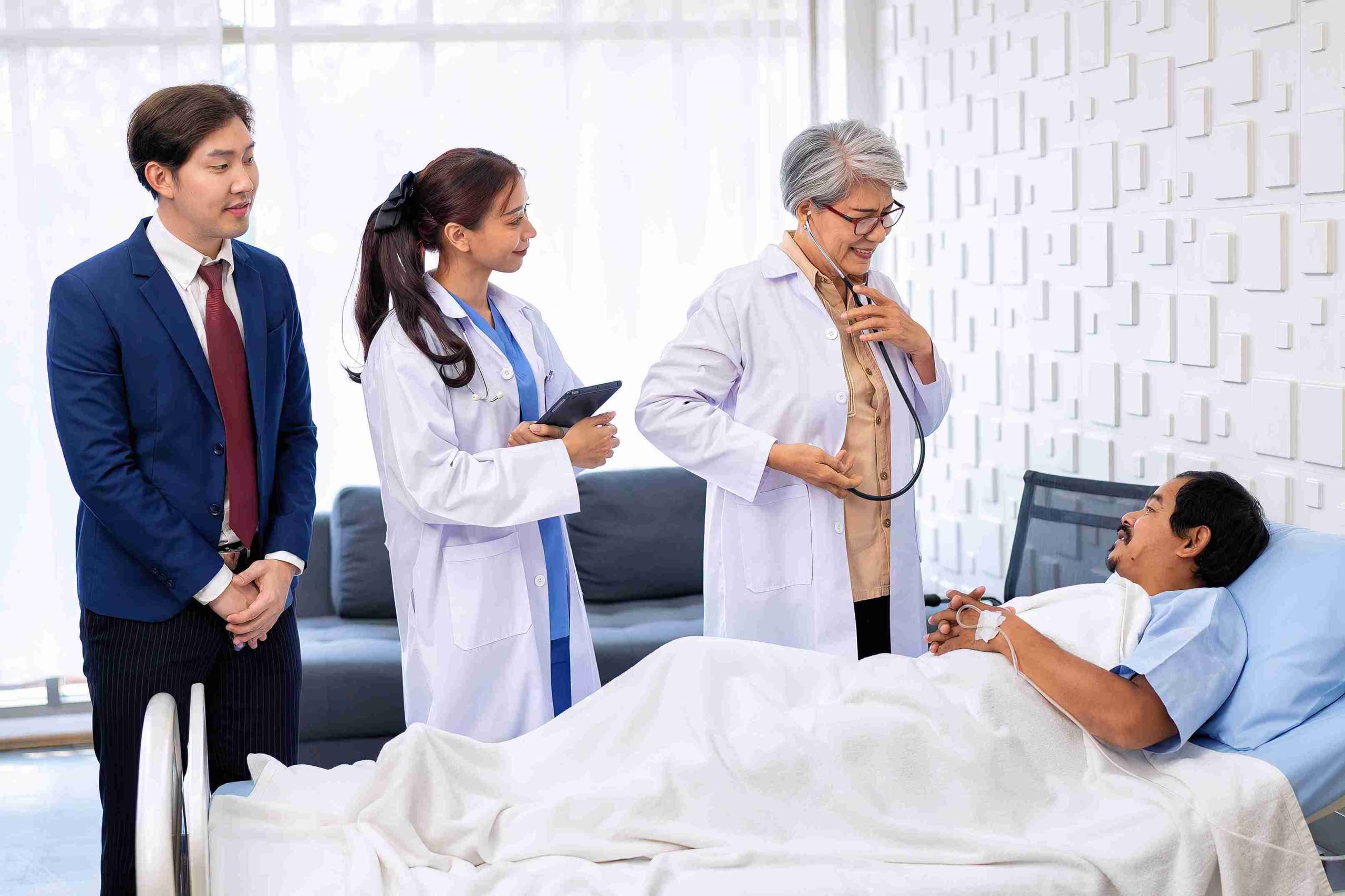 doctors visiting a male patient lying in the hospital bed
