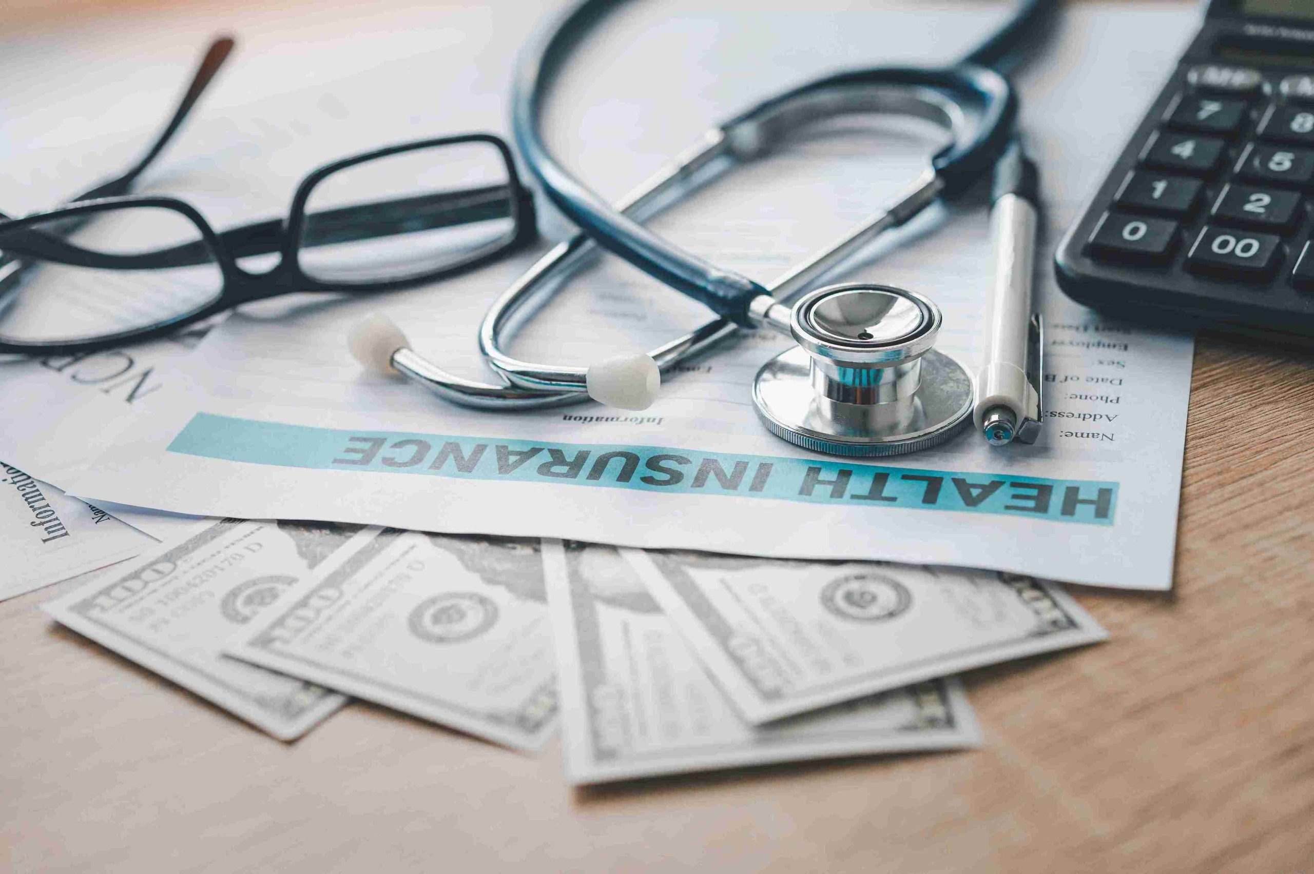 insurance papers with money and stethoscope