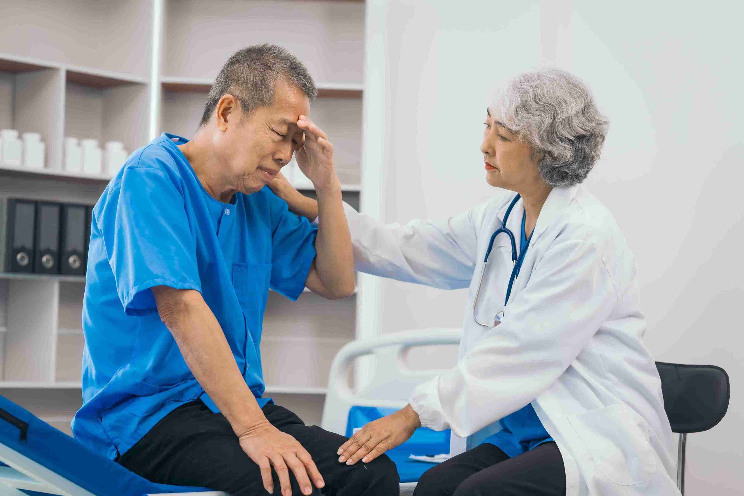 elderly male patient comforted by an elderly female doctor