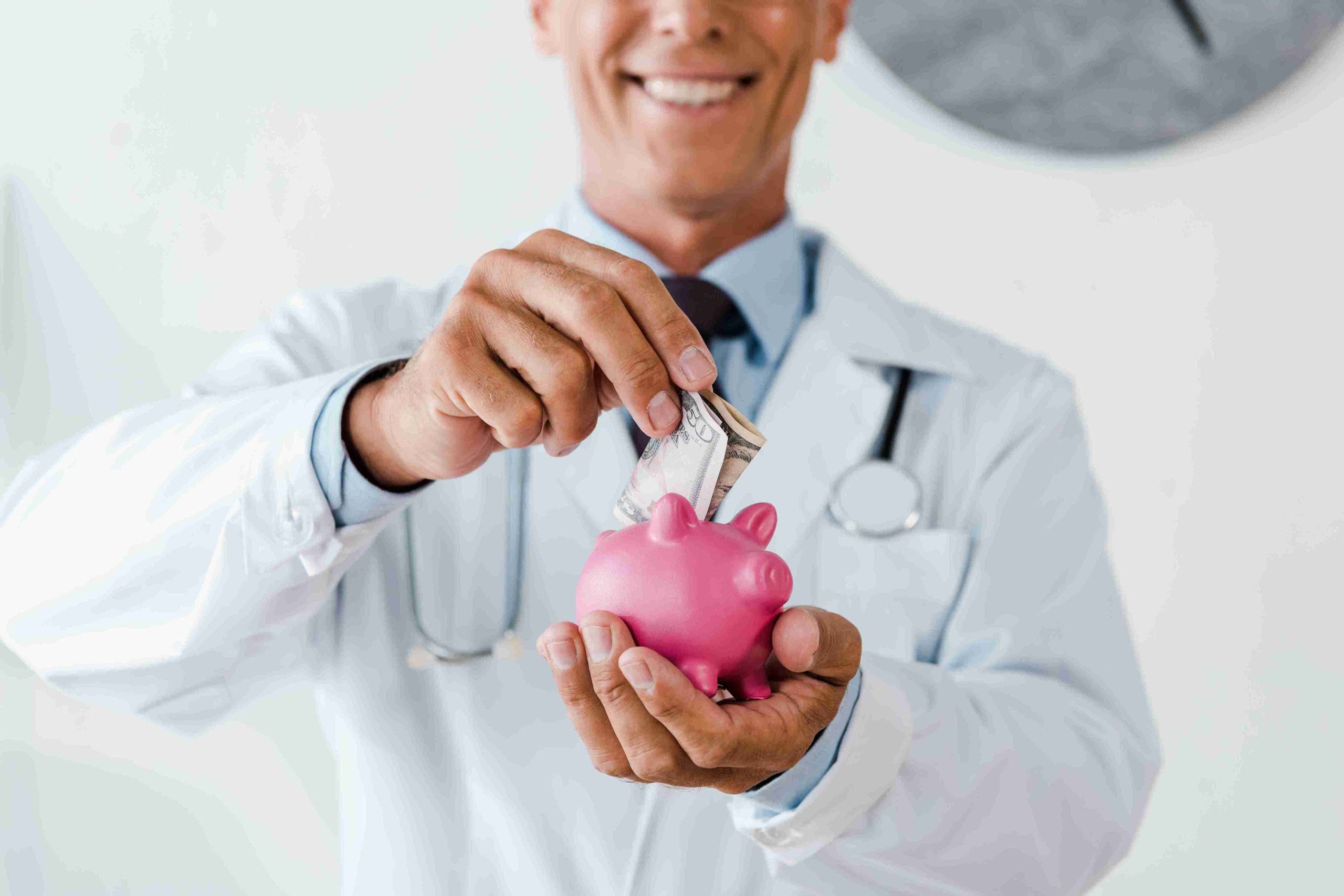 a doctor smiling ang putting money in a piggy bank