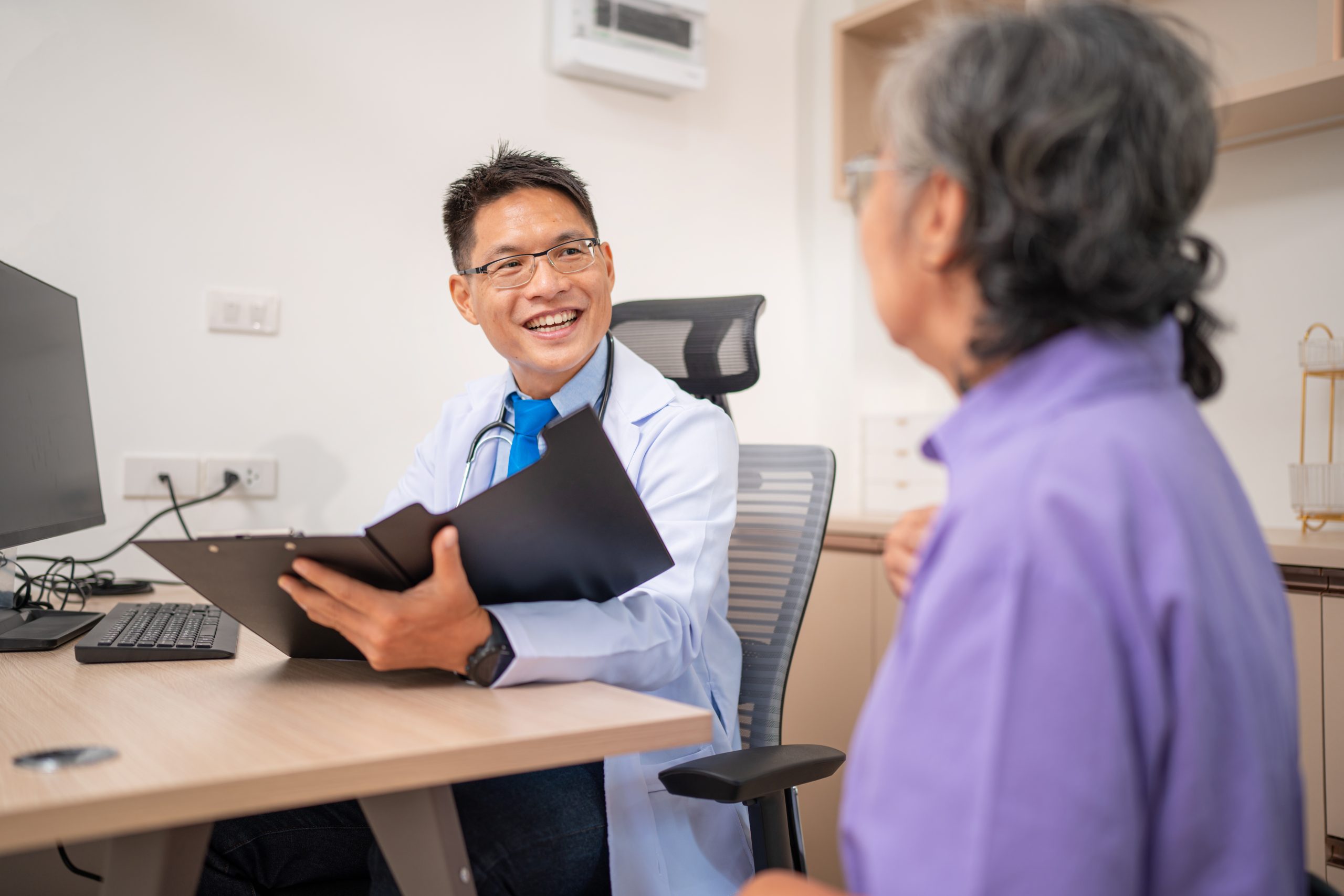 young male doctor smiling at elderly patient