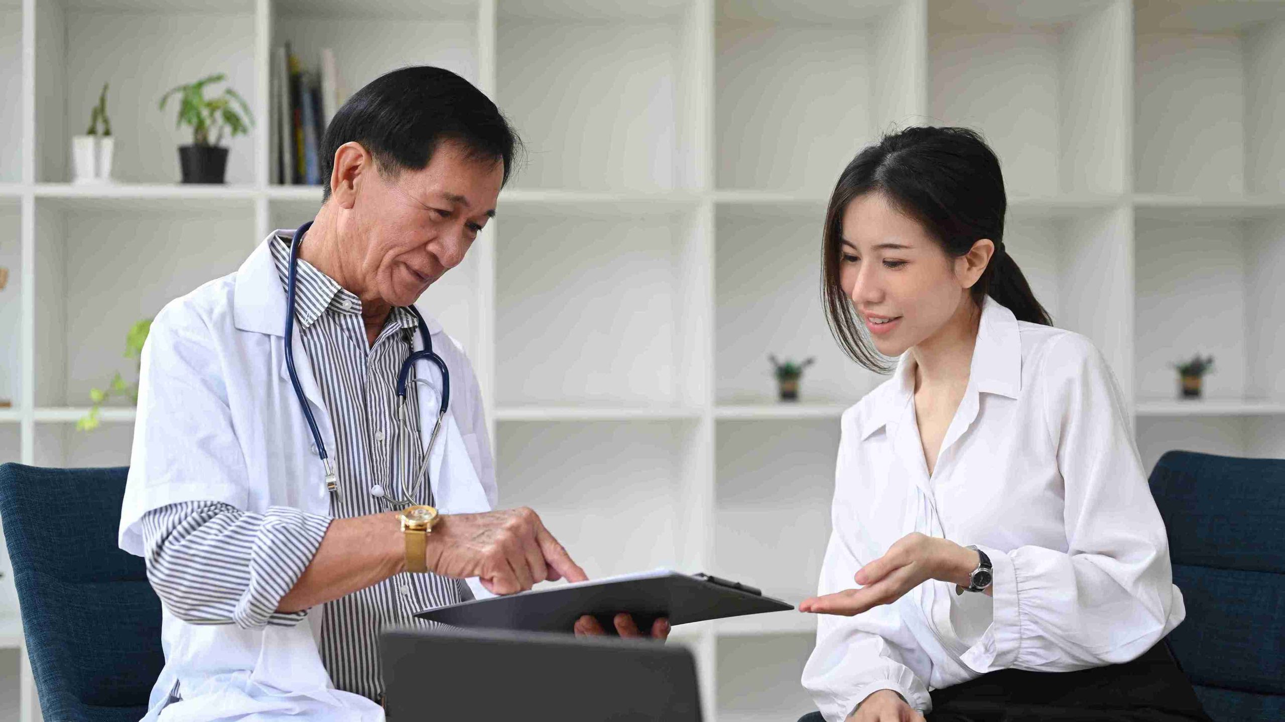 elderly male doctor speaking with a female patient