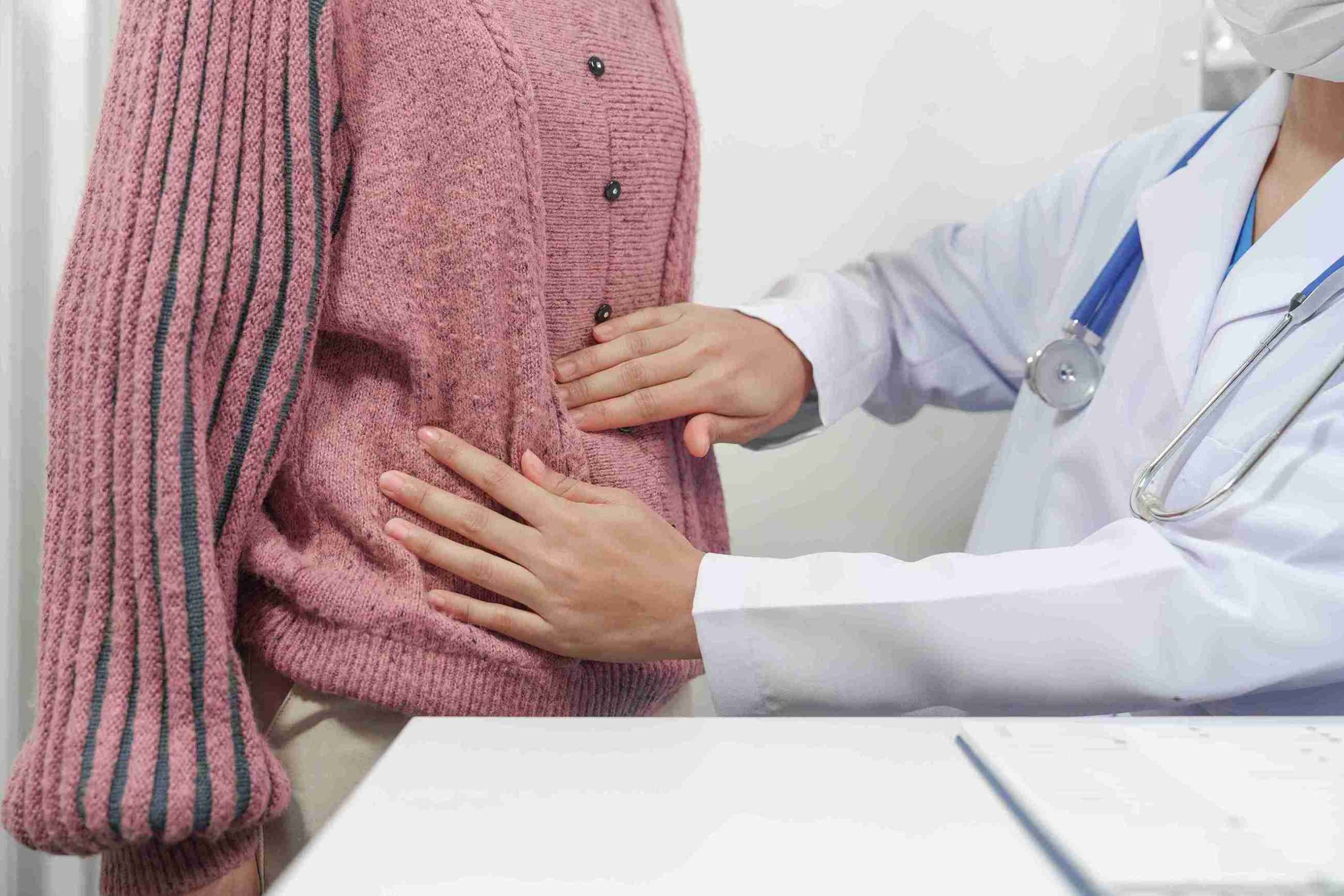 Female doctor examining the stomach of female patient