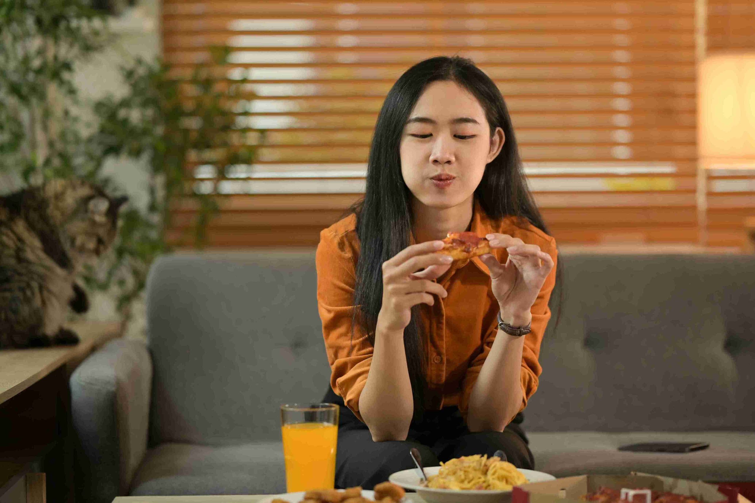 young woman happily eating at home