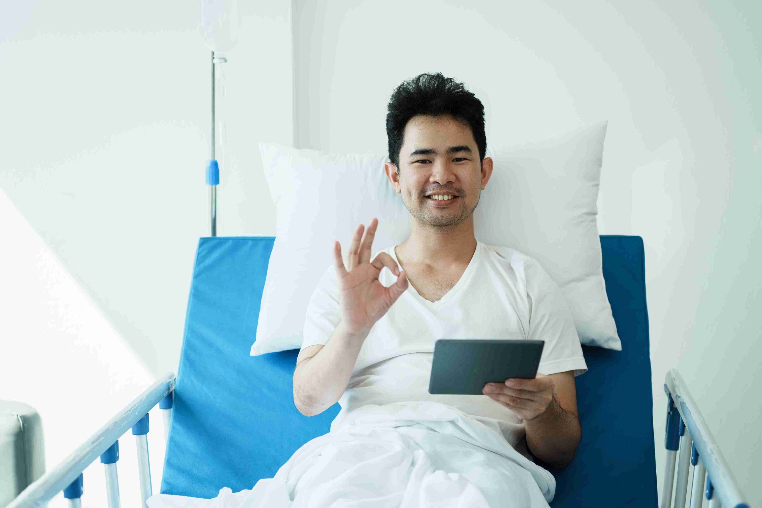 patient lying in a hospital bed giving the ok sign