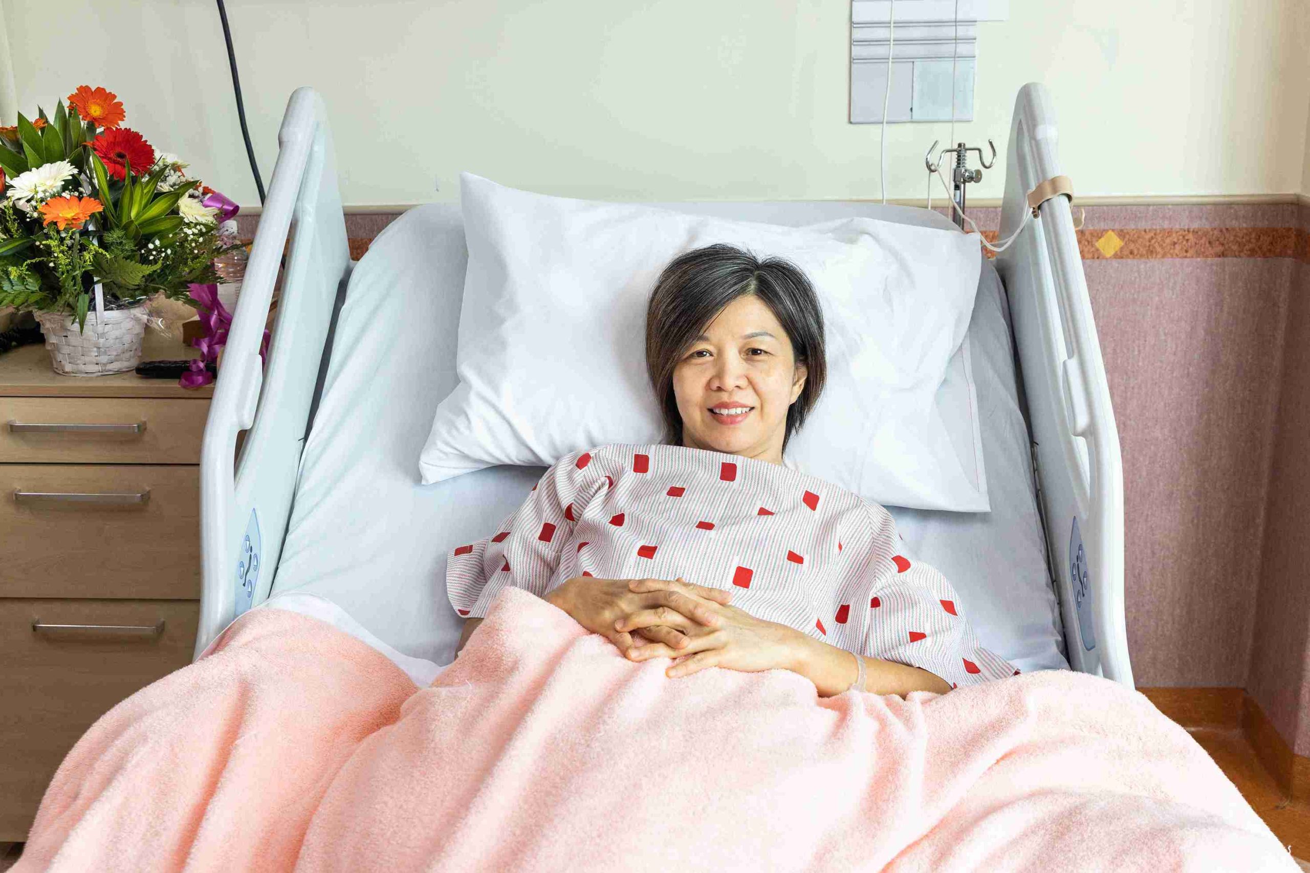 female patient lying in bed smiling at the camera