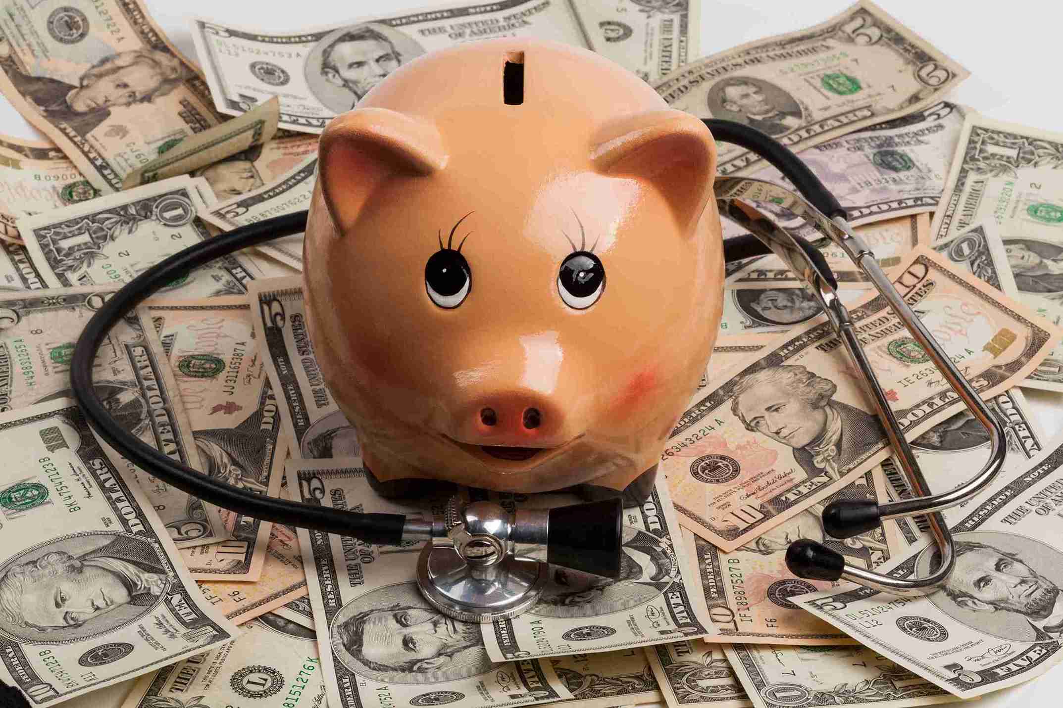 piggy bank and stethoscope on top of dollar bills