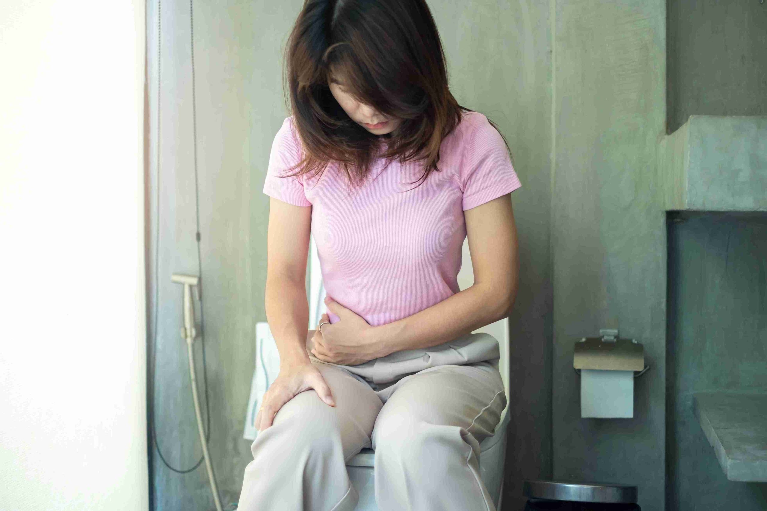 woman sitting in the toilet with her hand on her stomach
