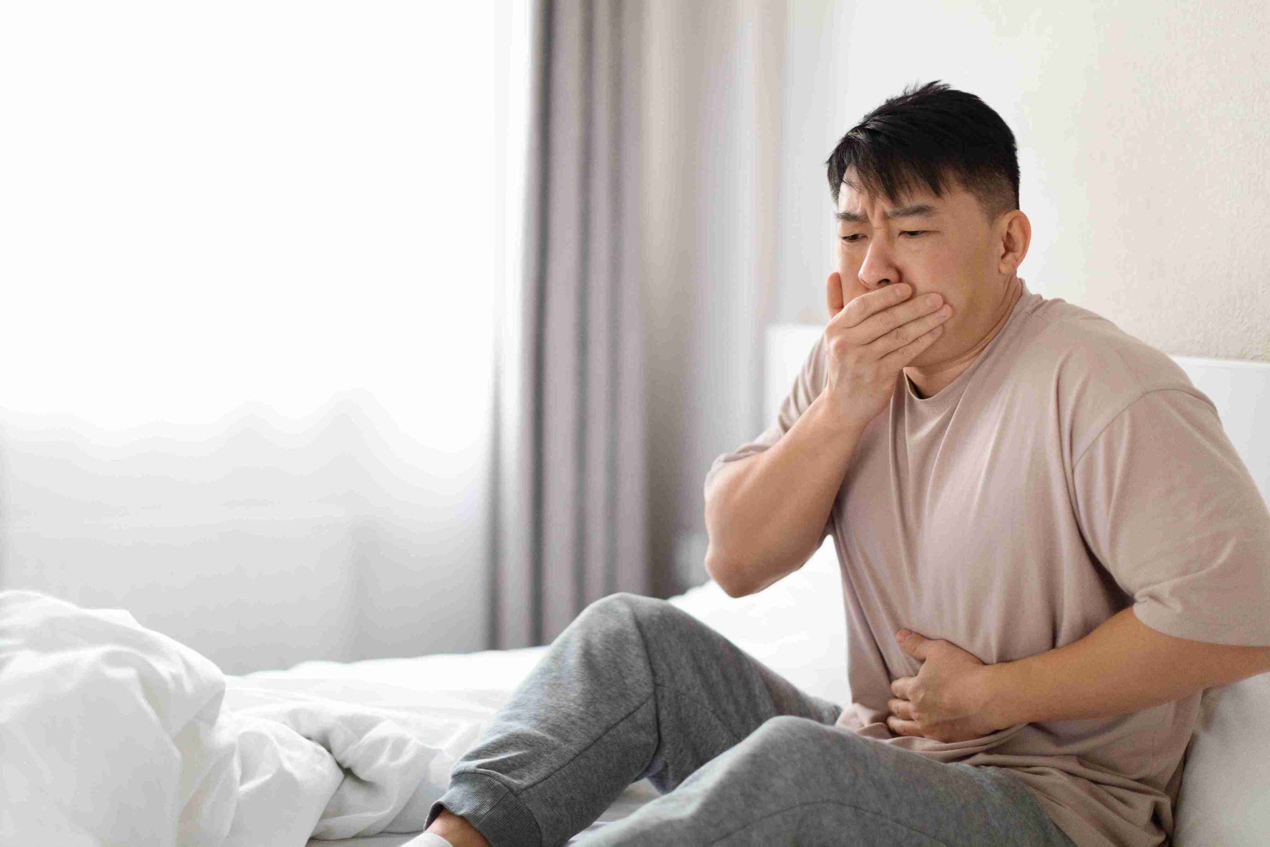 man sitting in bed with nausea