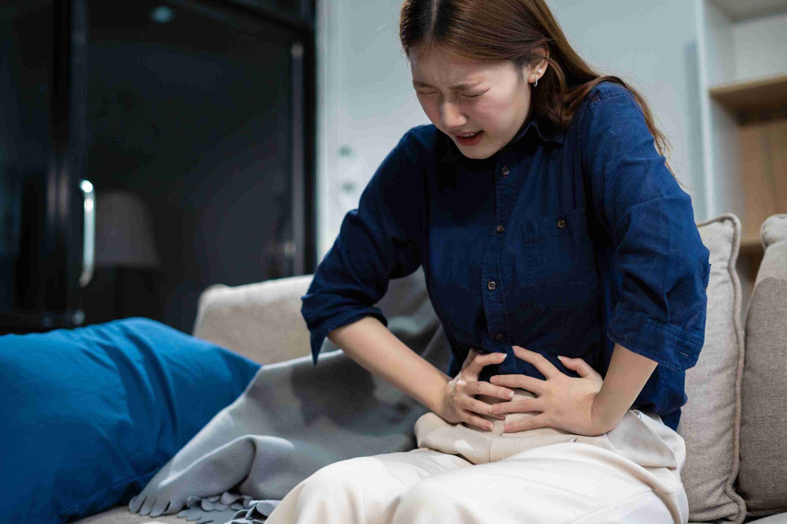 girl sitting in the sofa with stomach pain