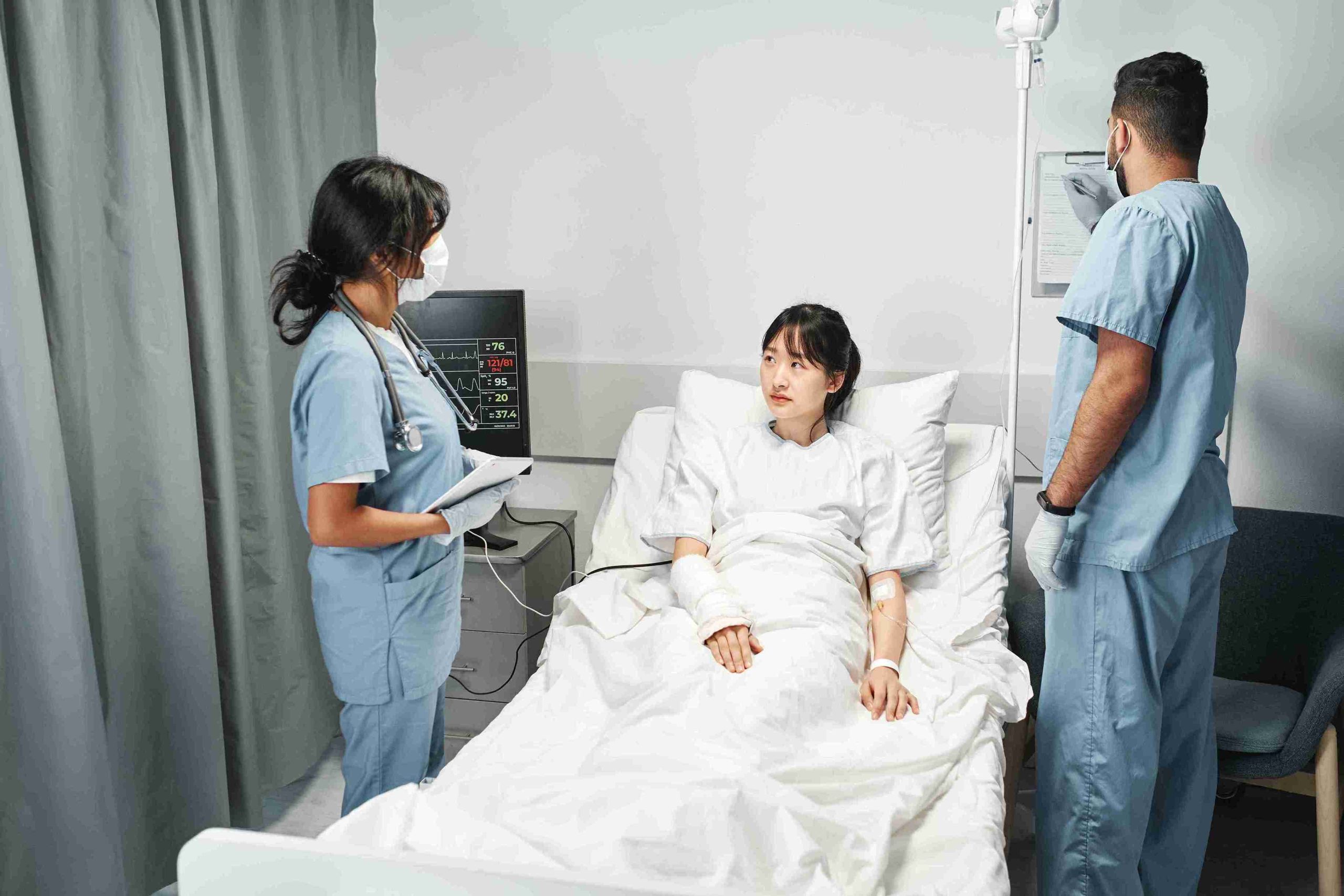 female patient in bed visited by two doctors
