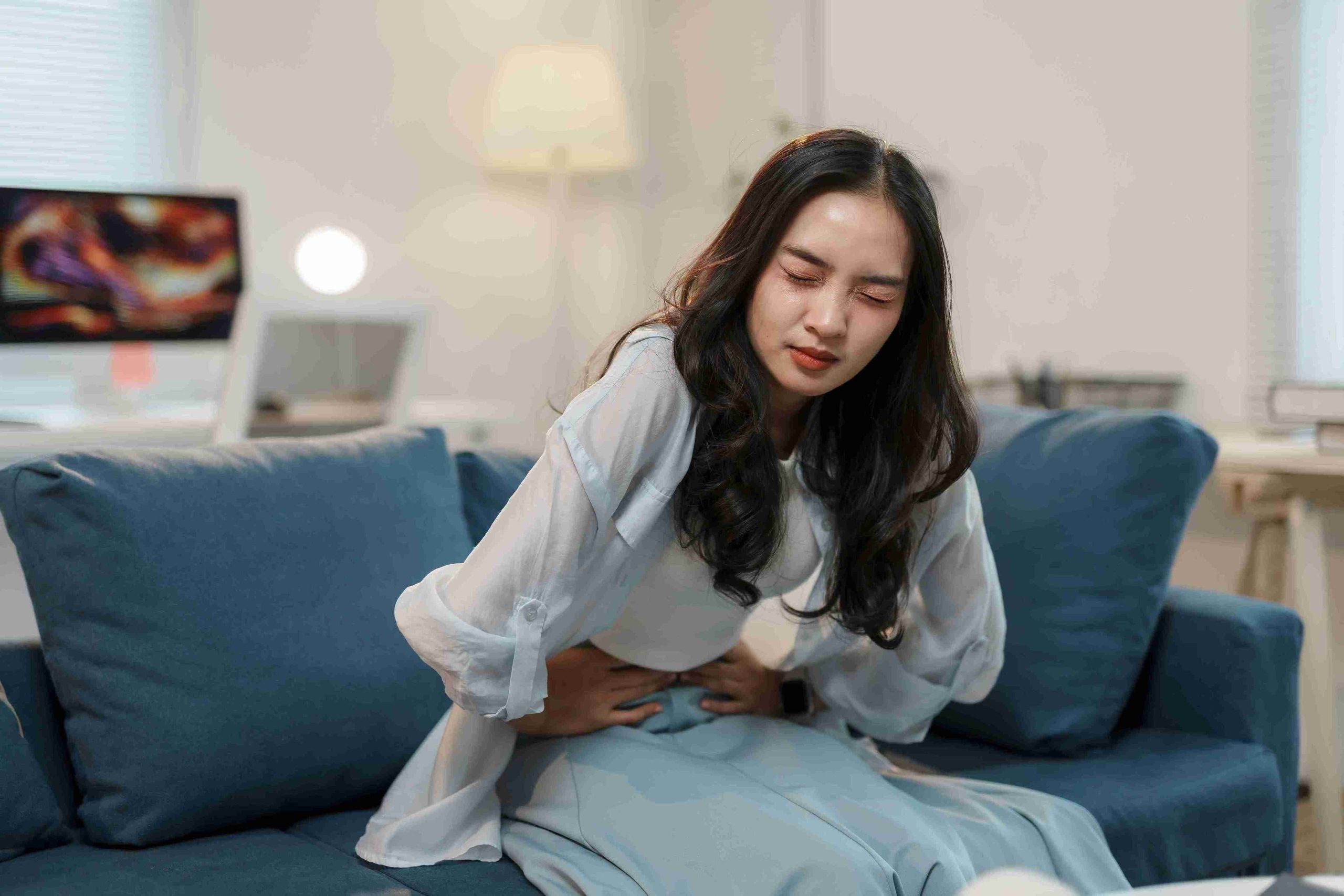 girl sitting in the couch with stomach pain