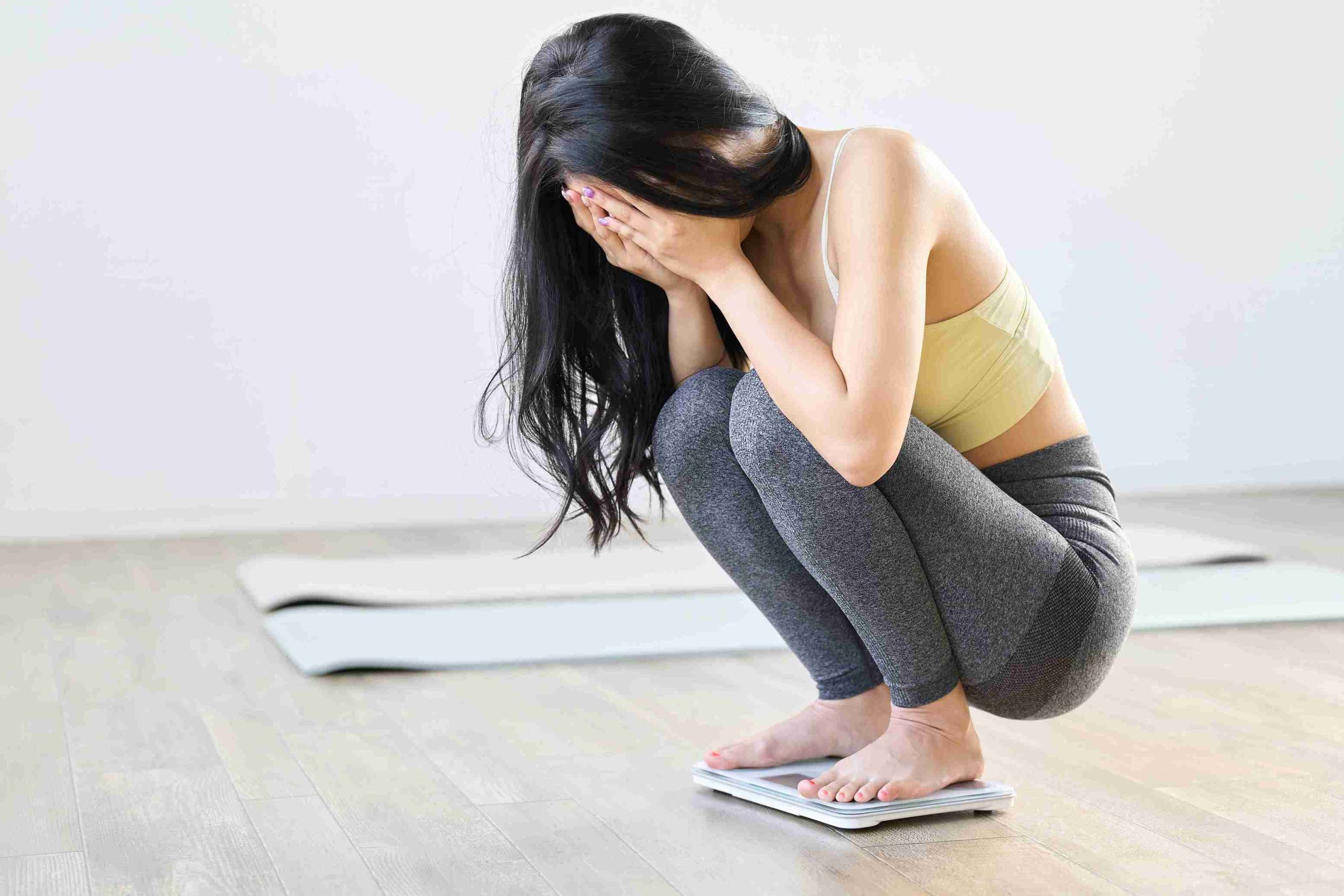 woman feeling depressed while on the weighing scale