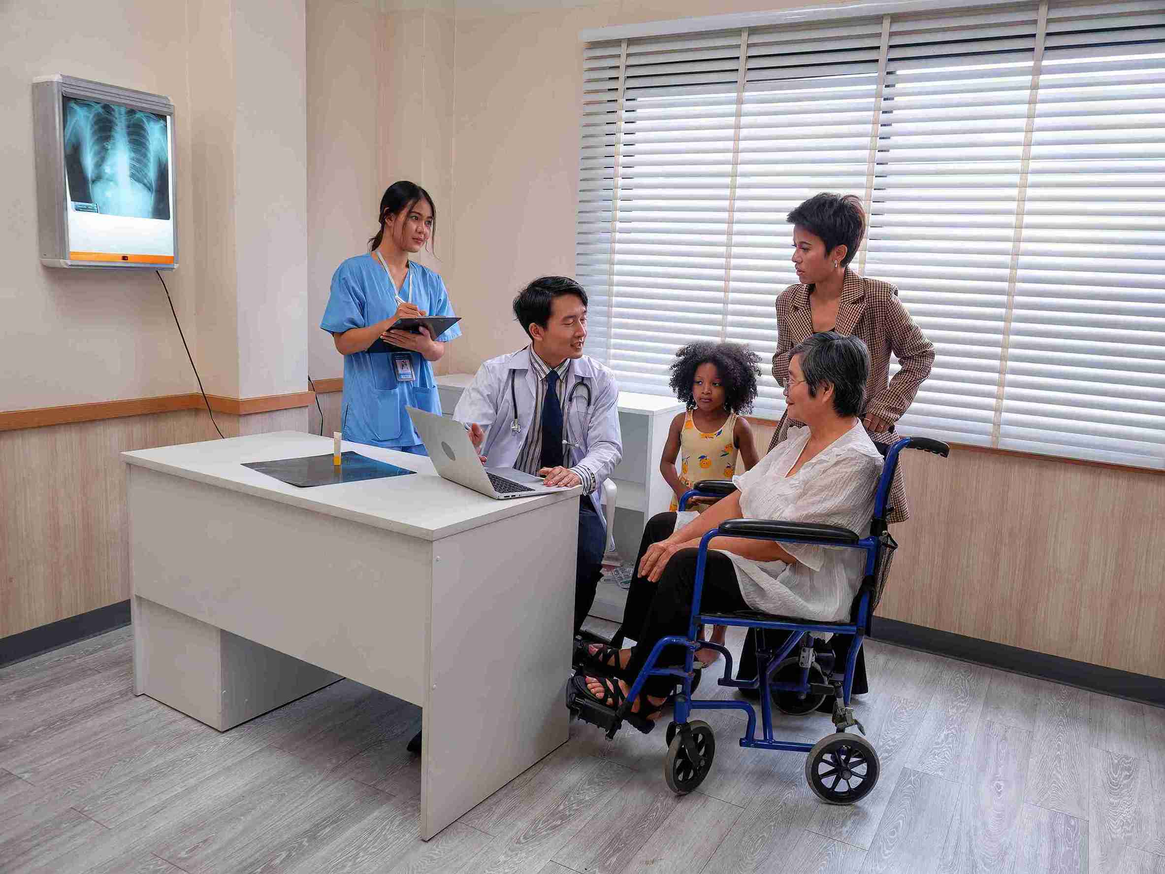 patient in wheelchair speaking with a doctor accompanied by her family