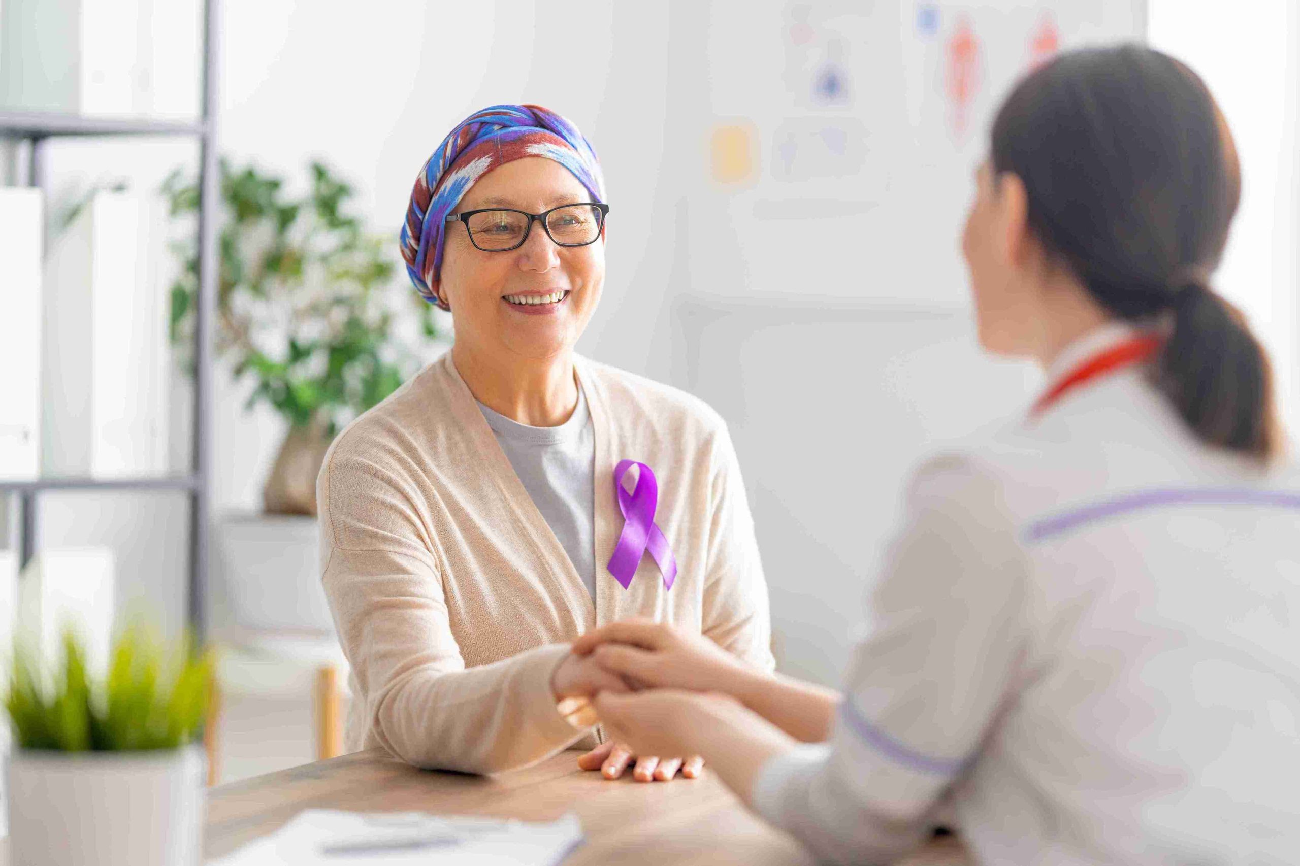 patient with cancer smiling at healthcare worker holding her hand