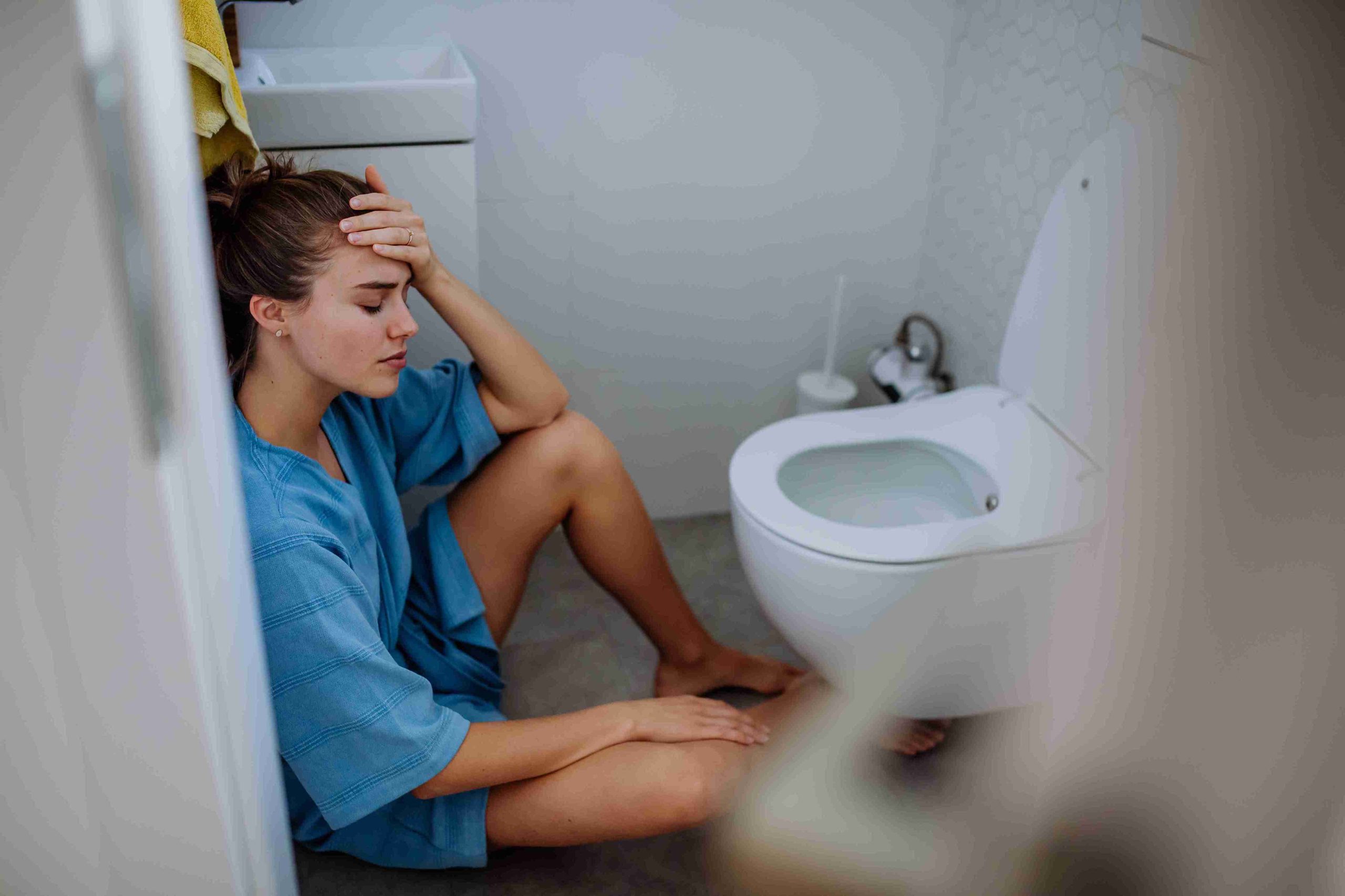woman sitting in front of a toilet bowl