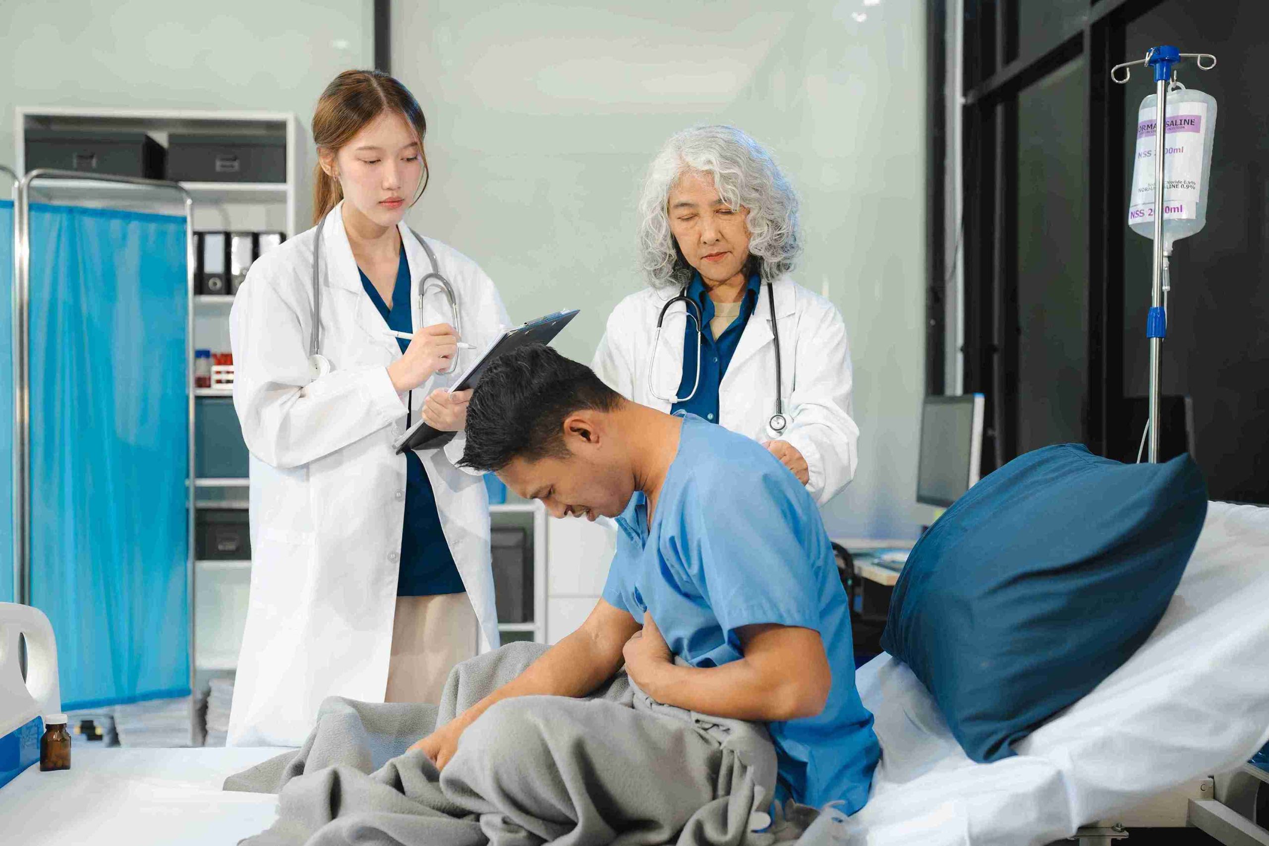 patient sitting in bed while 2 doctors are examining him