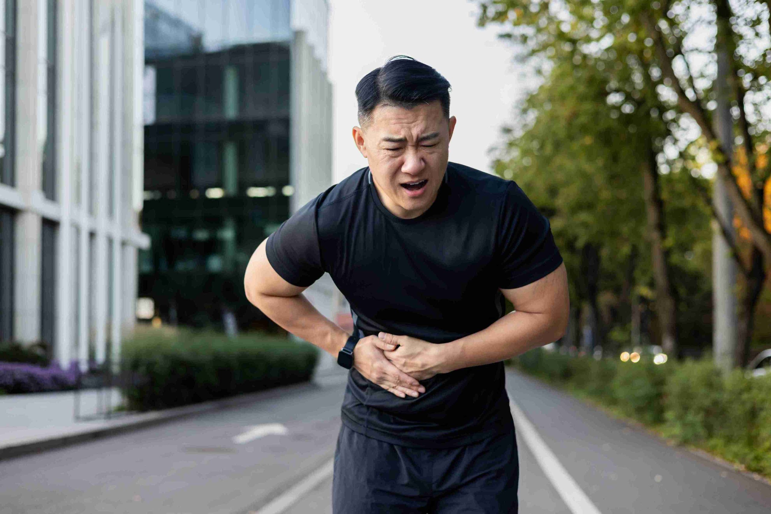 Male athlete bent over from pain in the stomach.