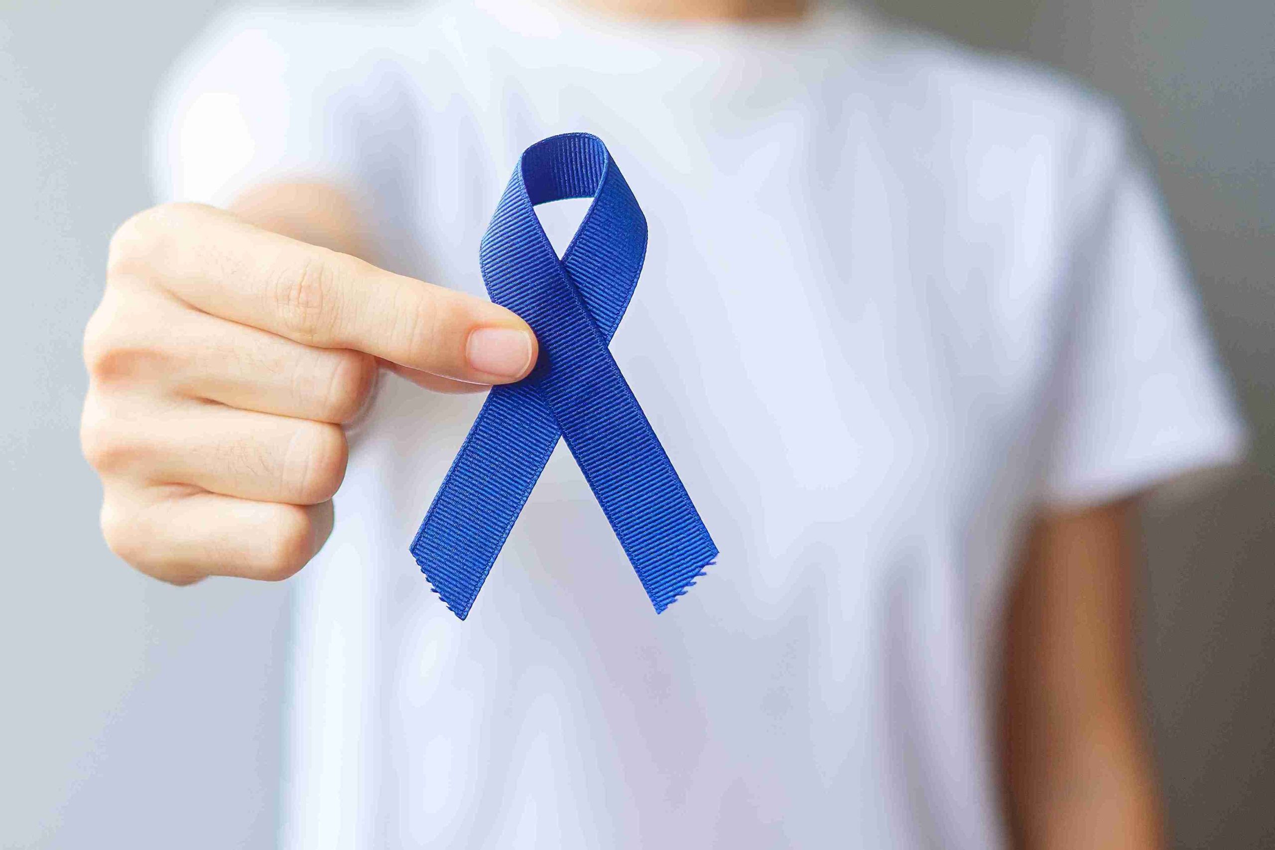 Person holding a blue ribbon for colon cancer.