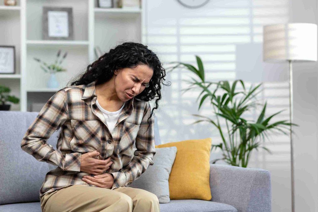 Woman sitting on the couch with gastric pain.