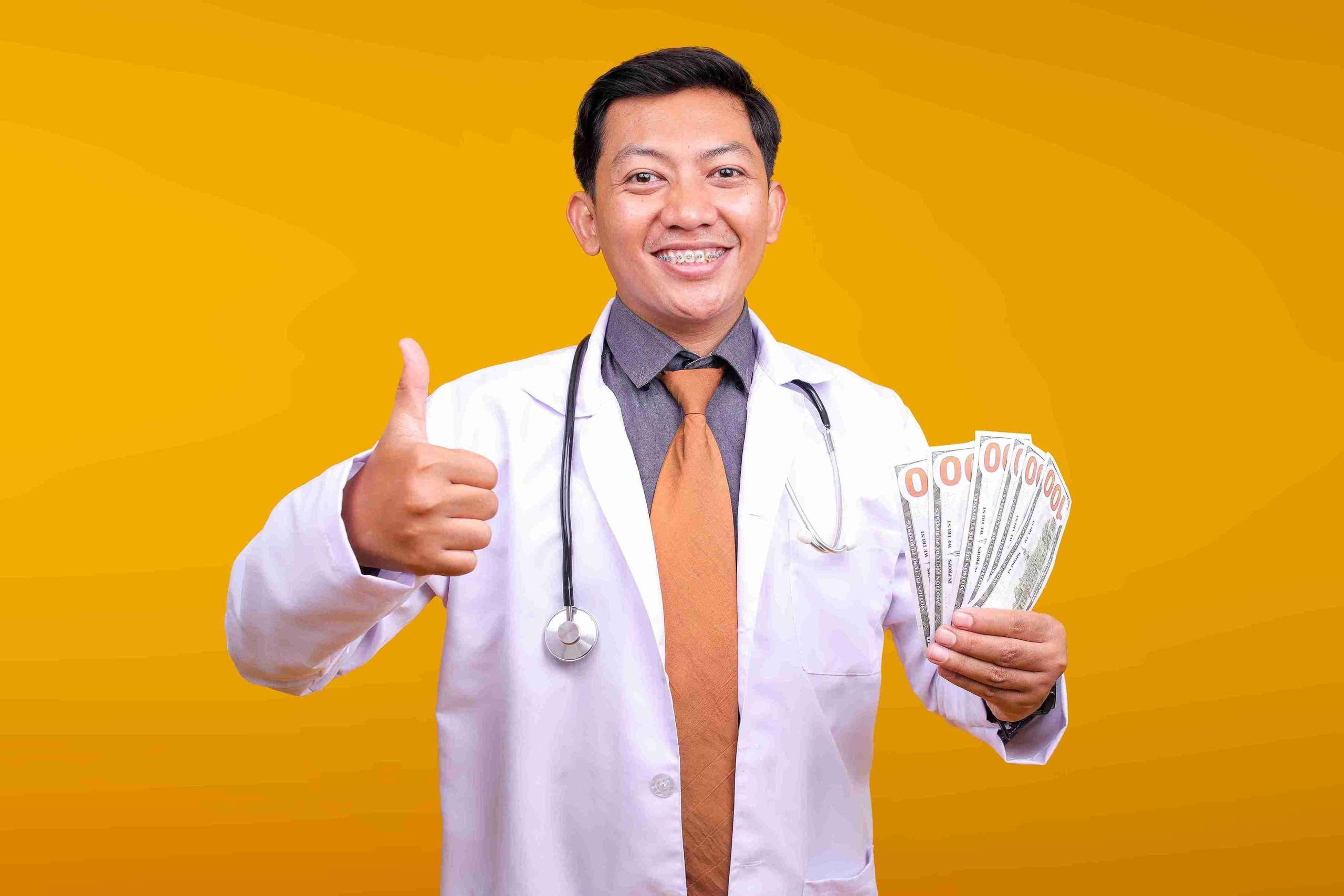 Doctor holding money and smiling while giving a thumbs up.