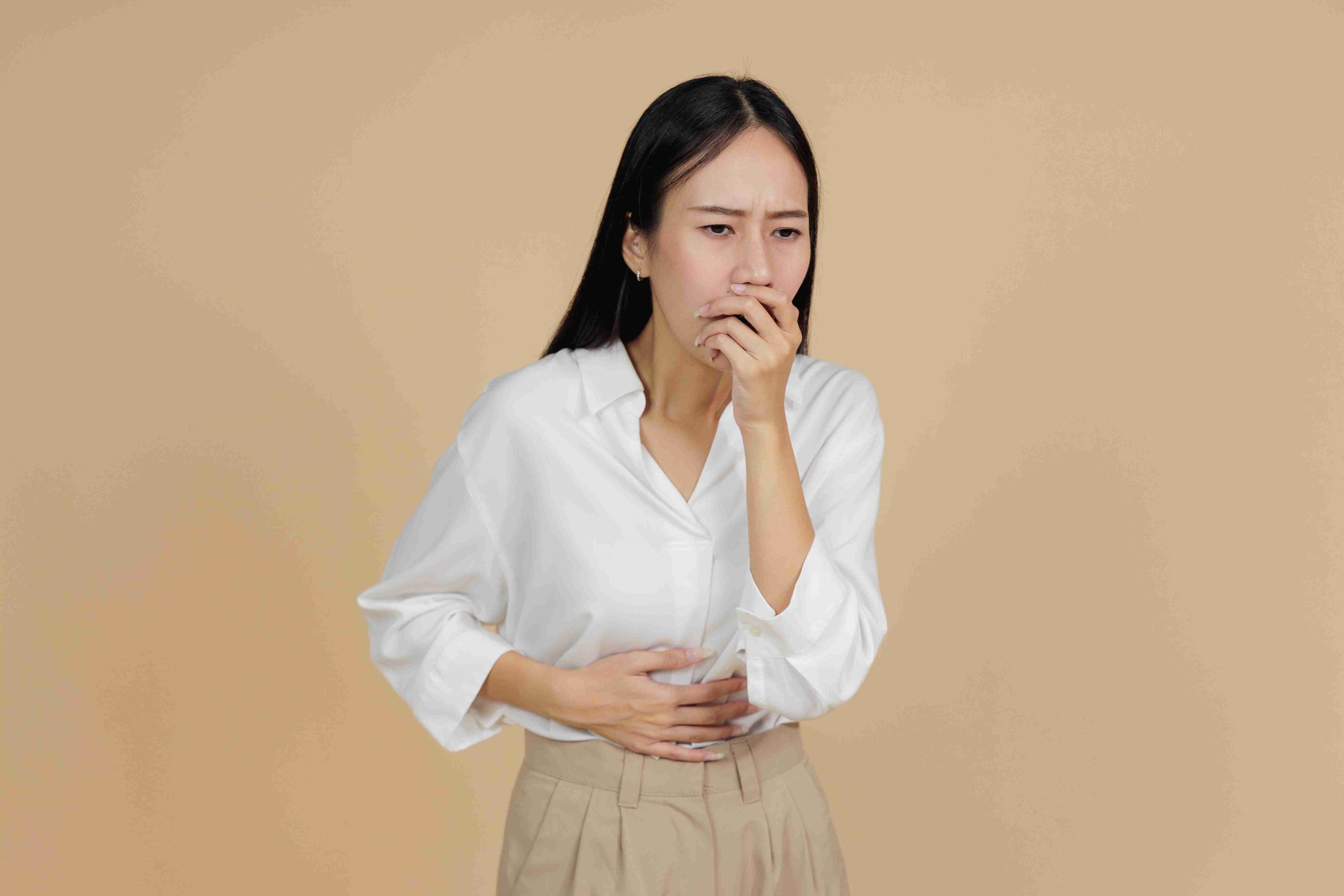 Woman standing and covering her mouth because of nausea.