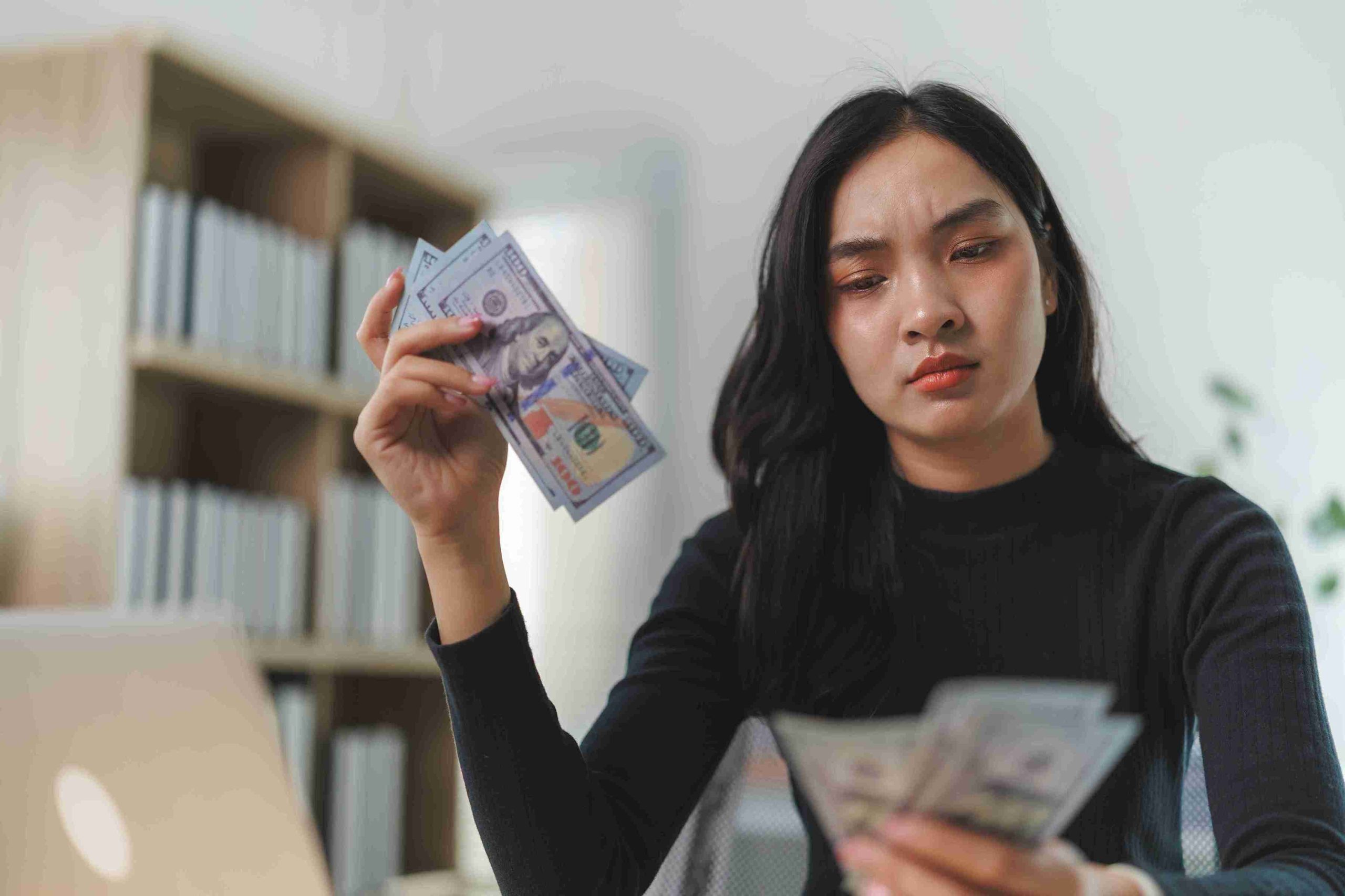 Woman counting money and looking confused.