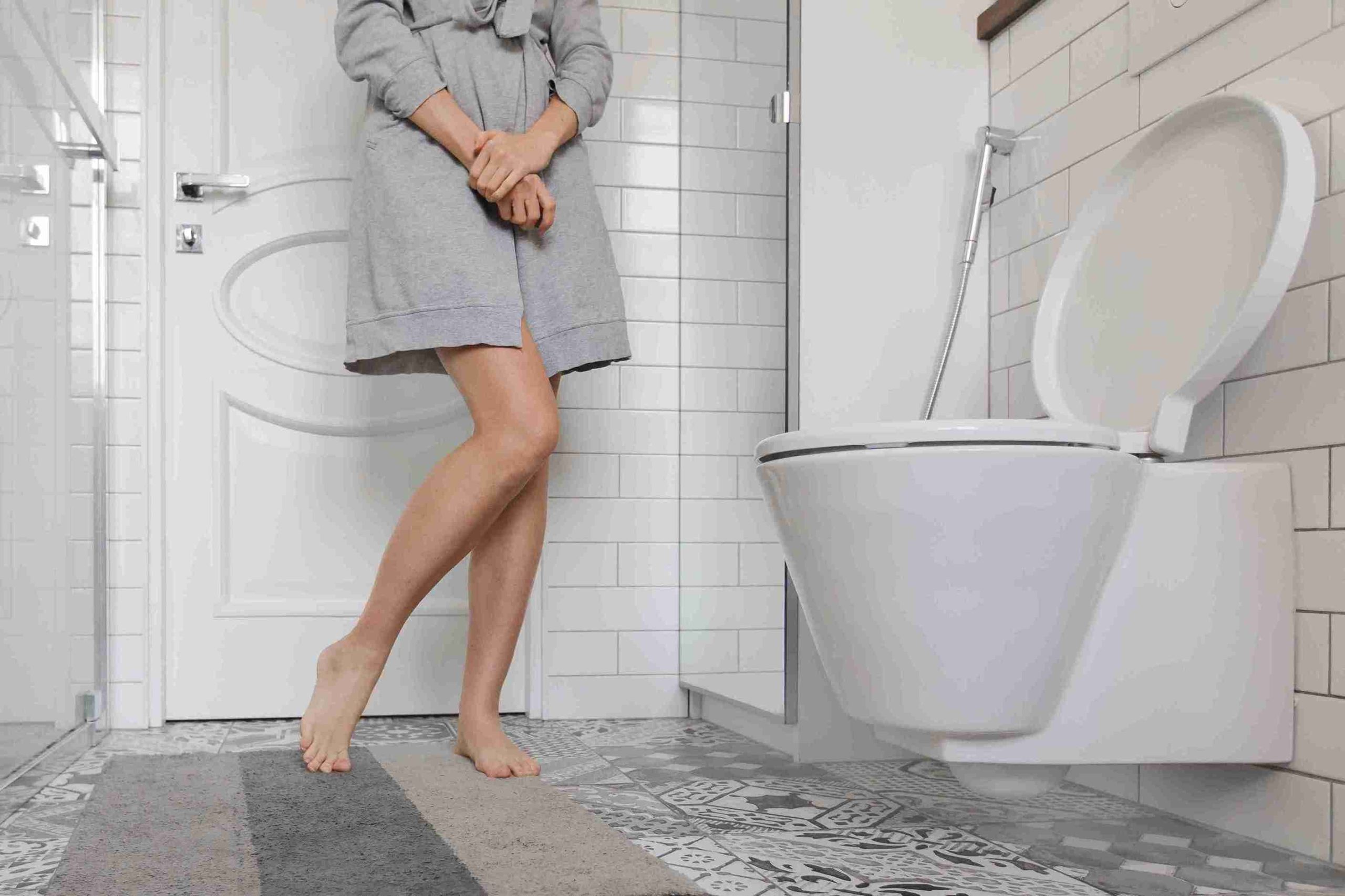 Woman standing looking at the toilet bowl.