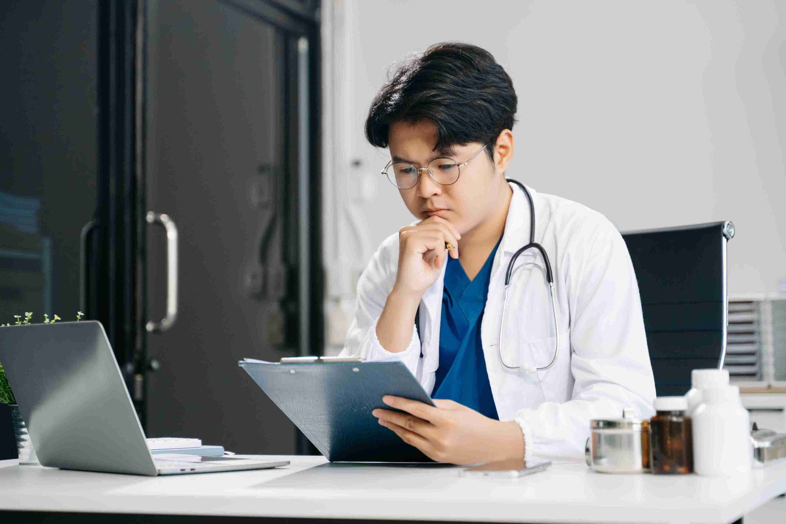 Young male doctor analyzing the results of a patient test.