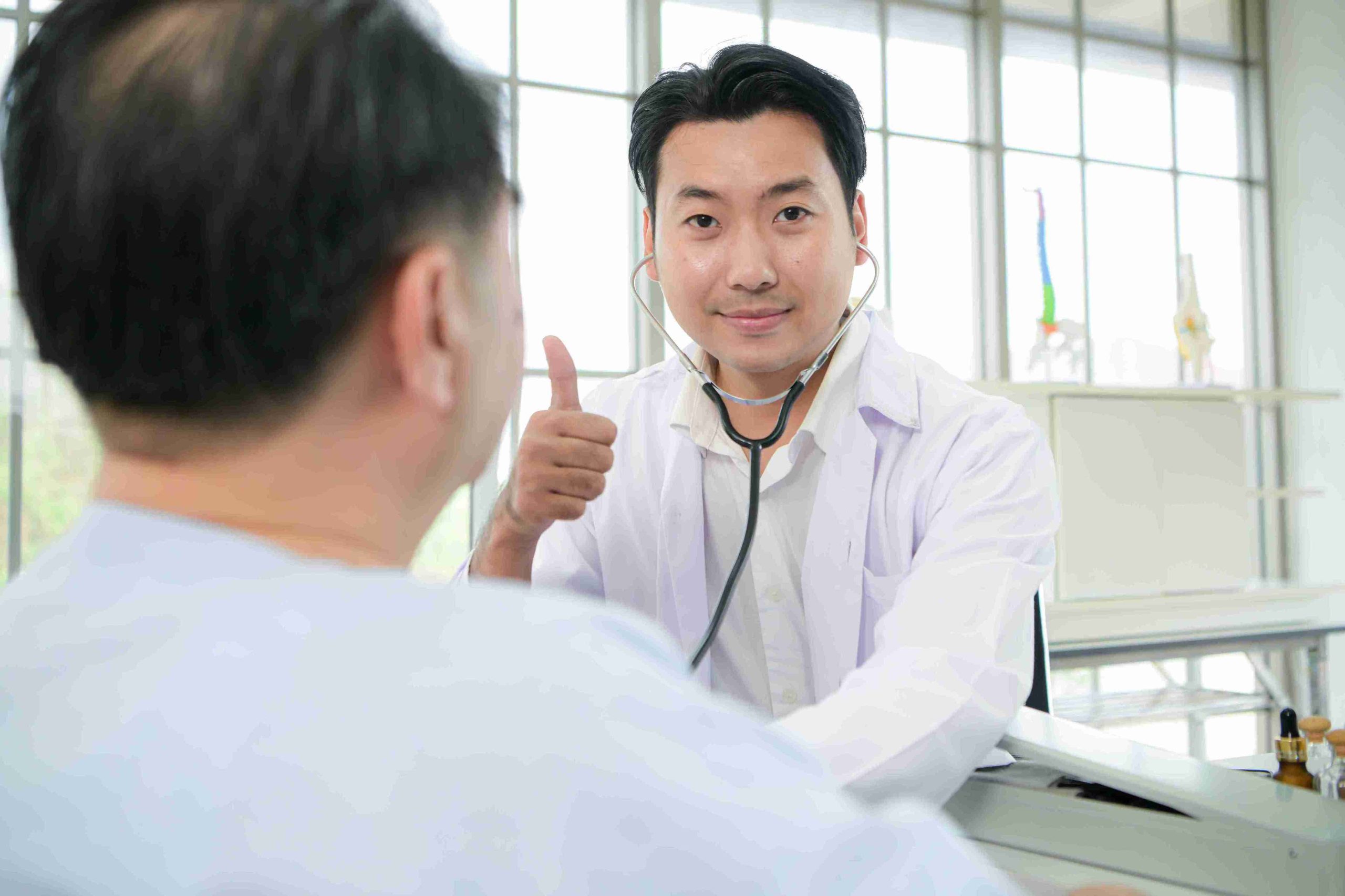 Doctor speaking with his patient and giving the thumbs up sign.