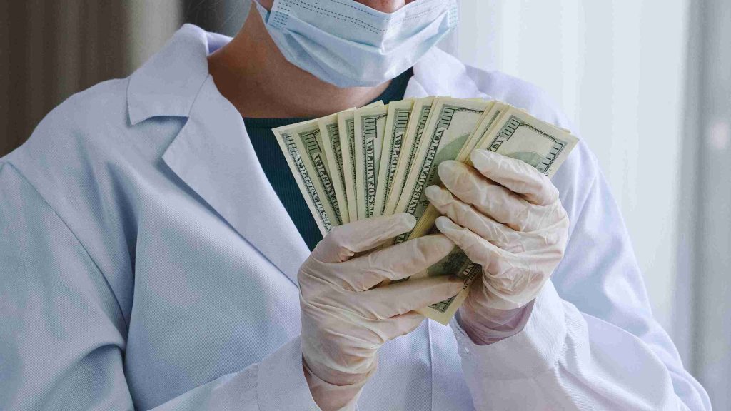 Healthcare worder holding dollar bills.
