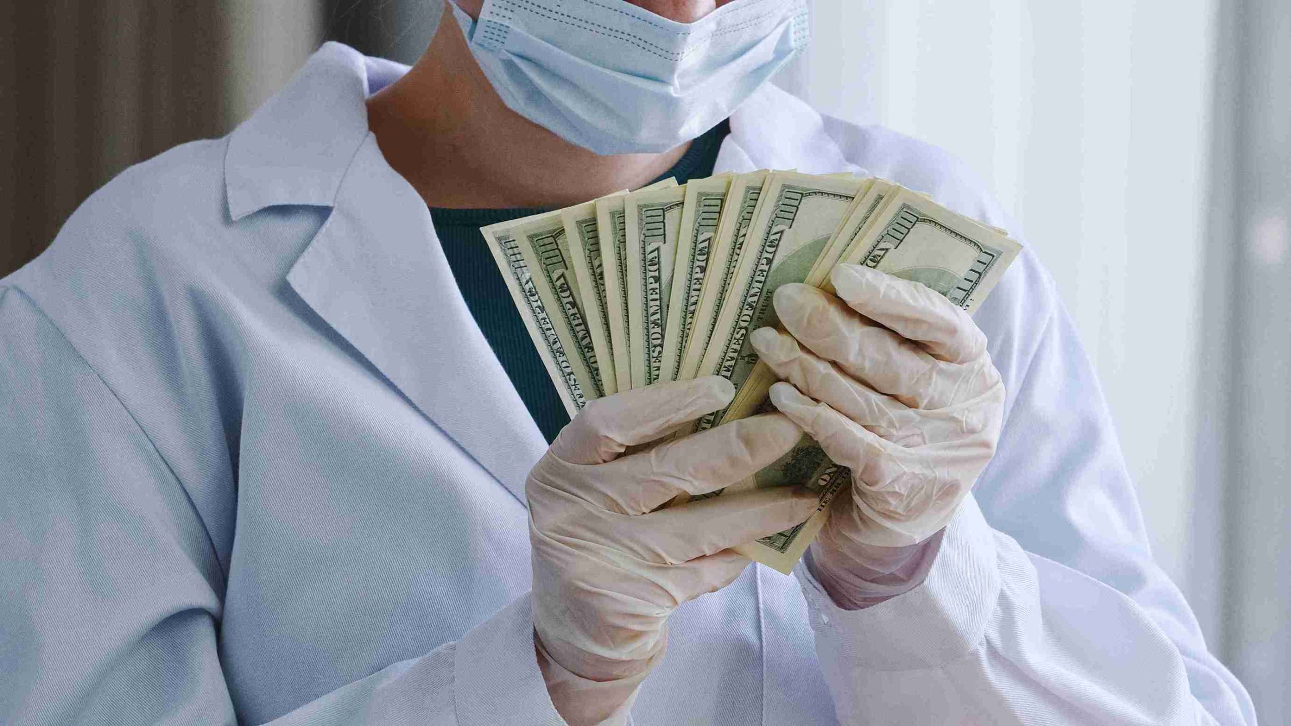Healthcare worder holding dollar bills.