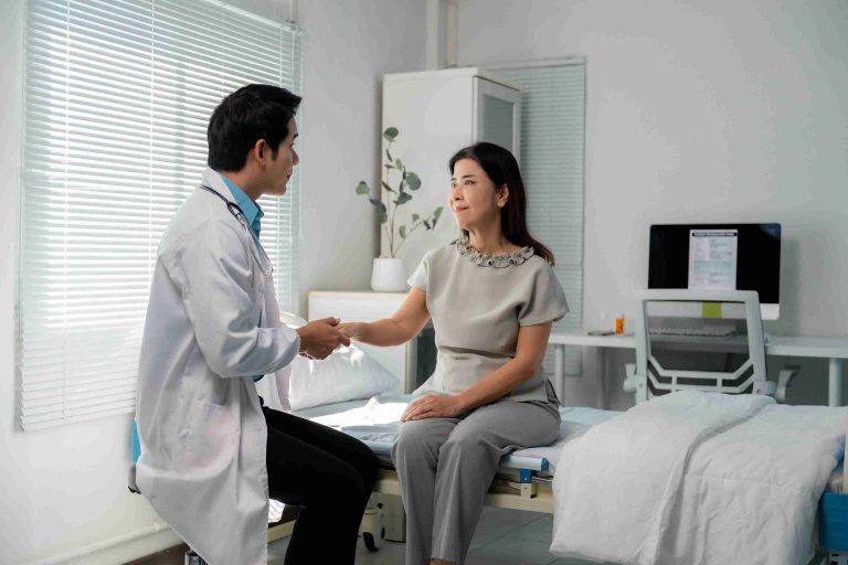 Young doctor comforting an elderly patient by holding her hand.