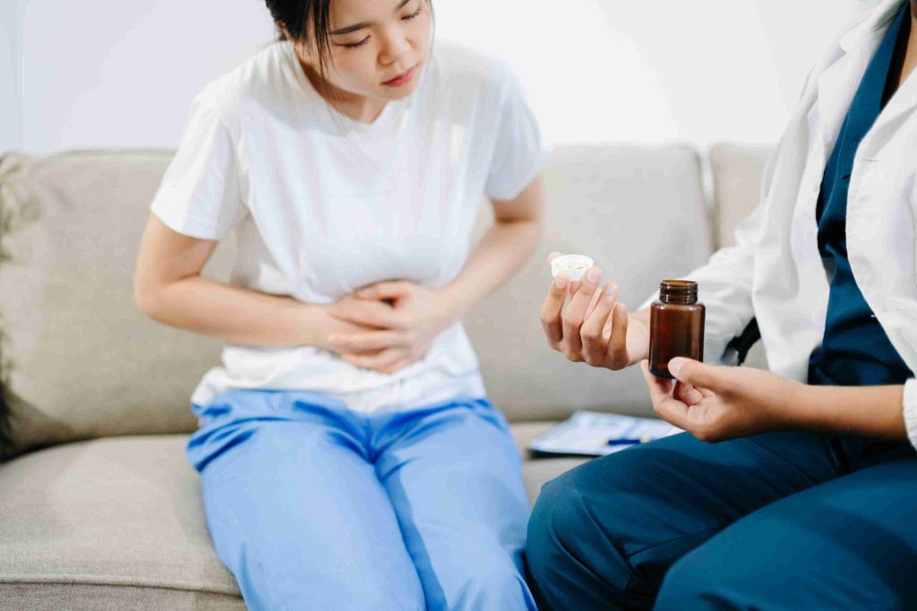 Healthcare professional providing medication to patient with gastric pain.