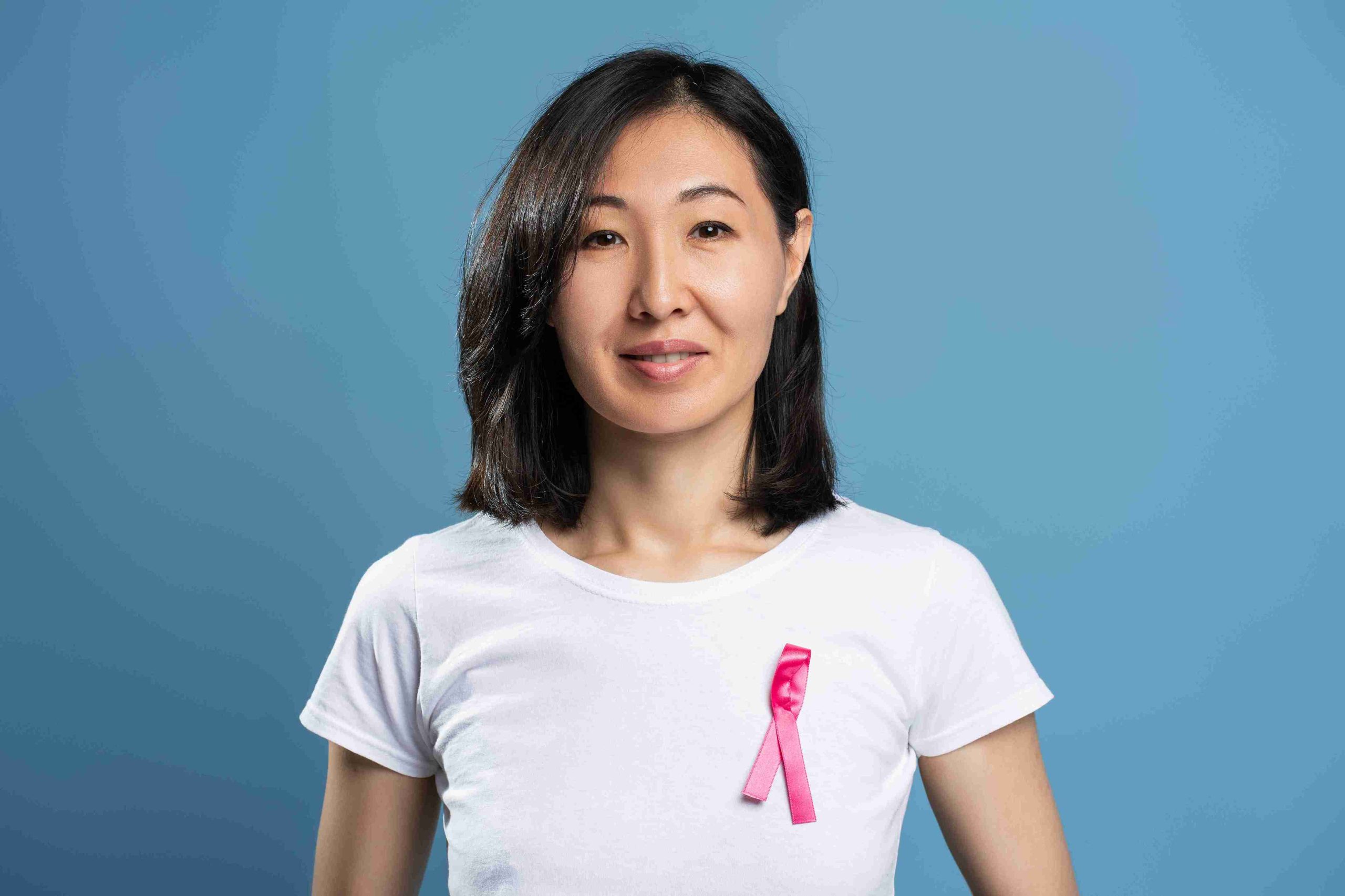 Woman smiling and wearing ribbon in support of cancer.