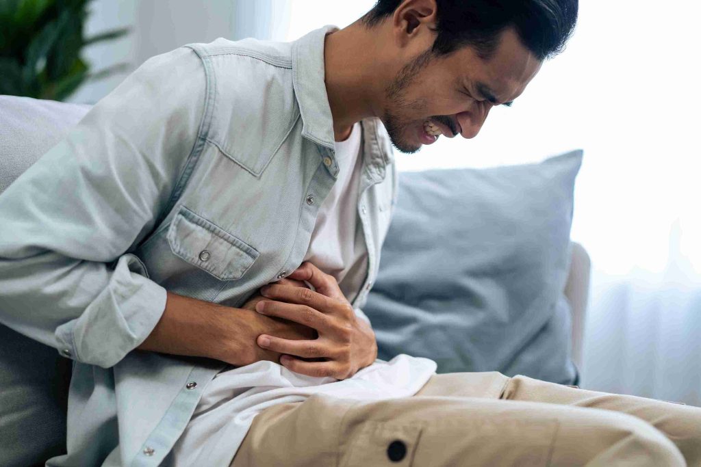 Young male sitting with severe gastric pain.