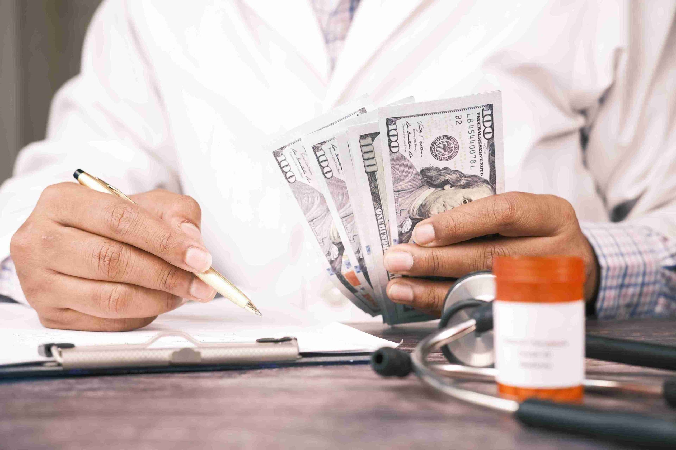 Doctor counting dollar bills and writing.
