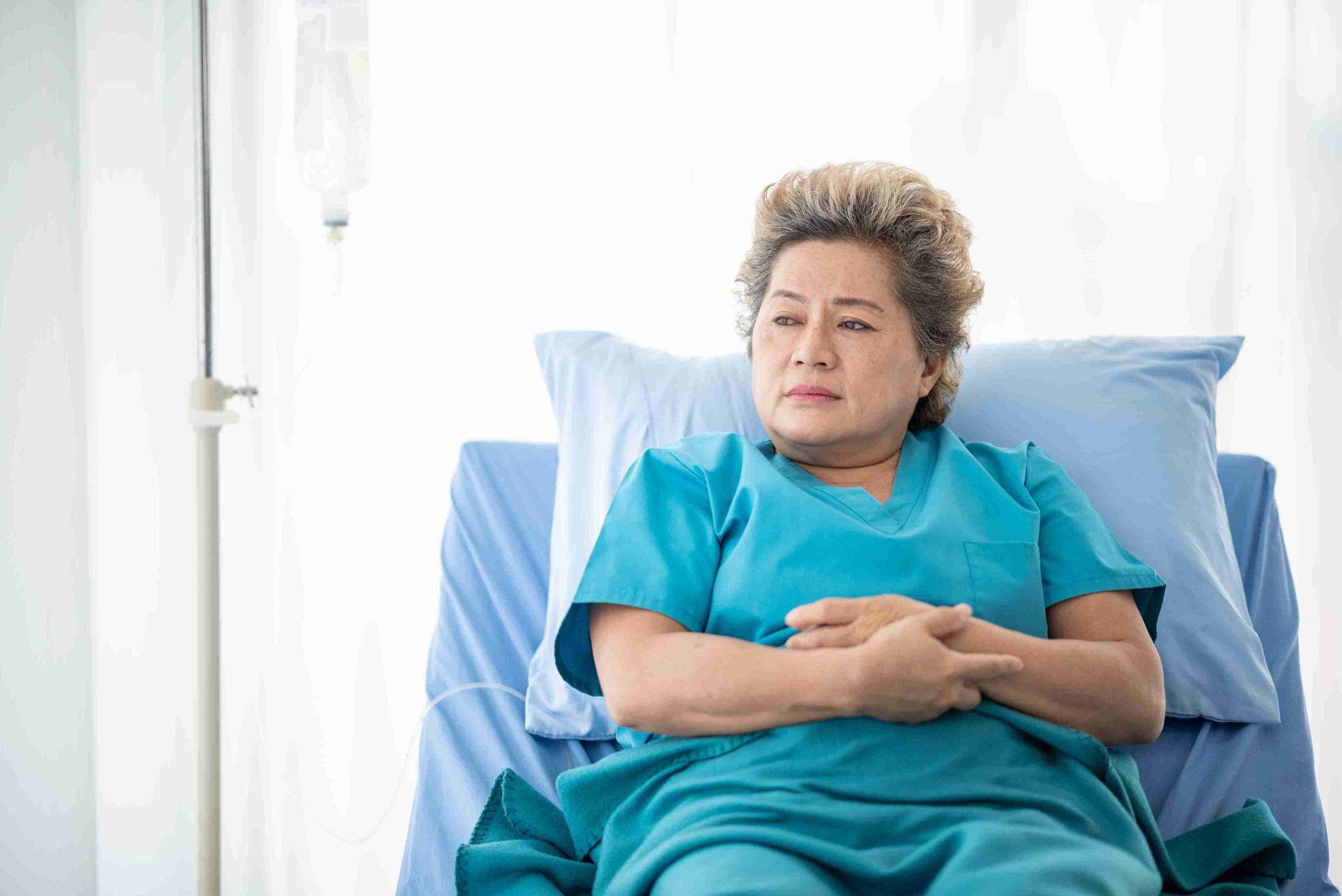 Elderly female patient lying in the hospital bed and thinking about something.