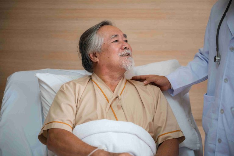Smiling elderly patient speaking with his doctor at his hospital bed.