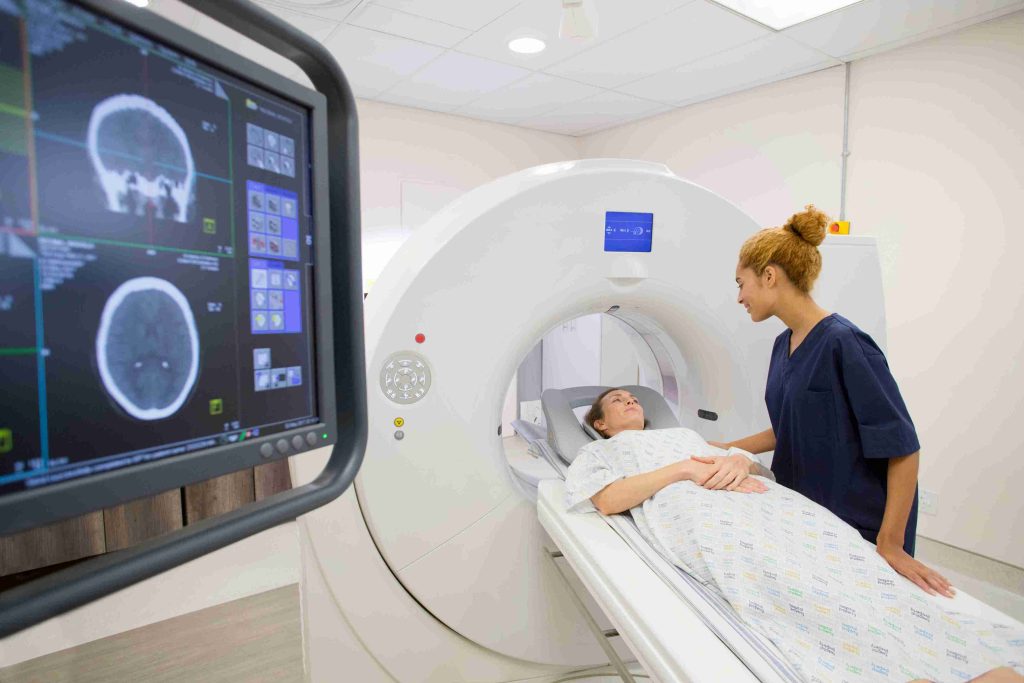 Healthcare worker talking to a patient lying in the CT scan machine.