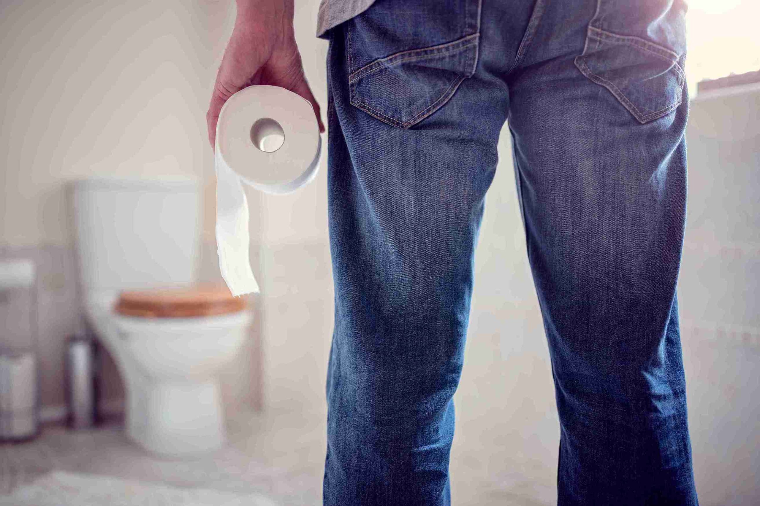 Man holding a toilet paper roll in the bathroom.